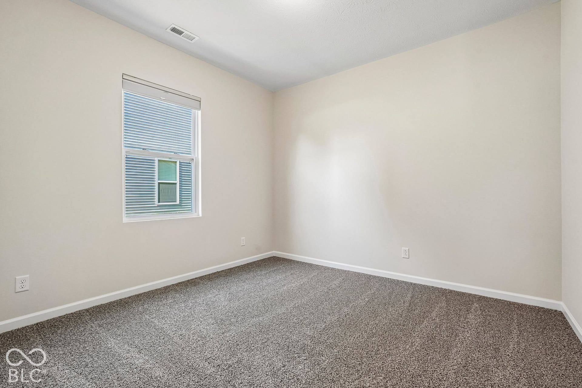 Neutral wall paint, textured carpeting, white trim, and a window with blinds