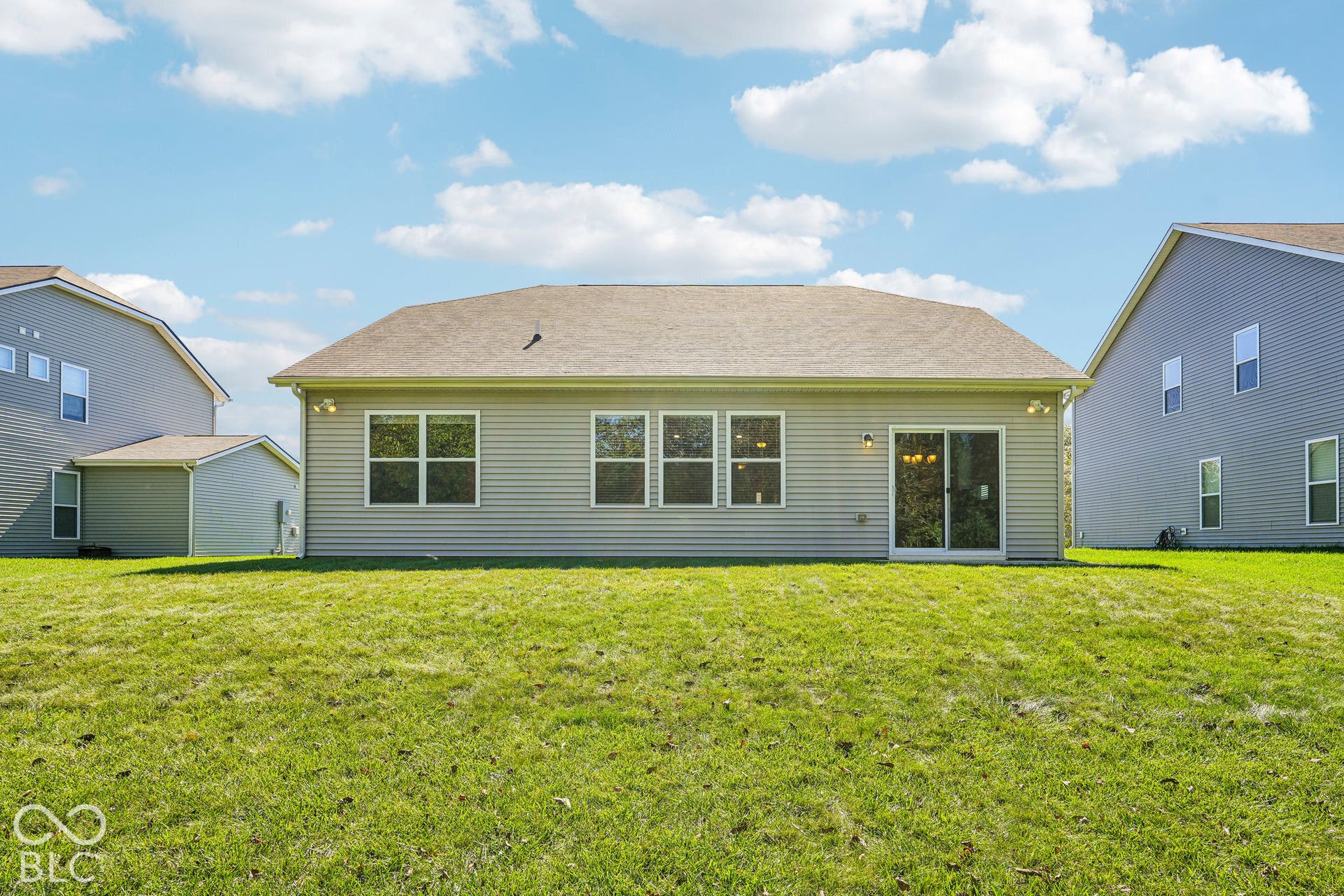 Expansive green lawn surrounds the exterior, featuring horizontal siding and a hip roof