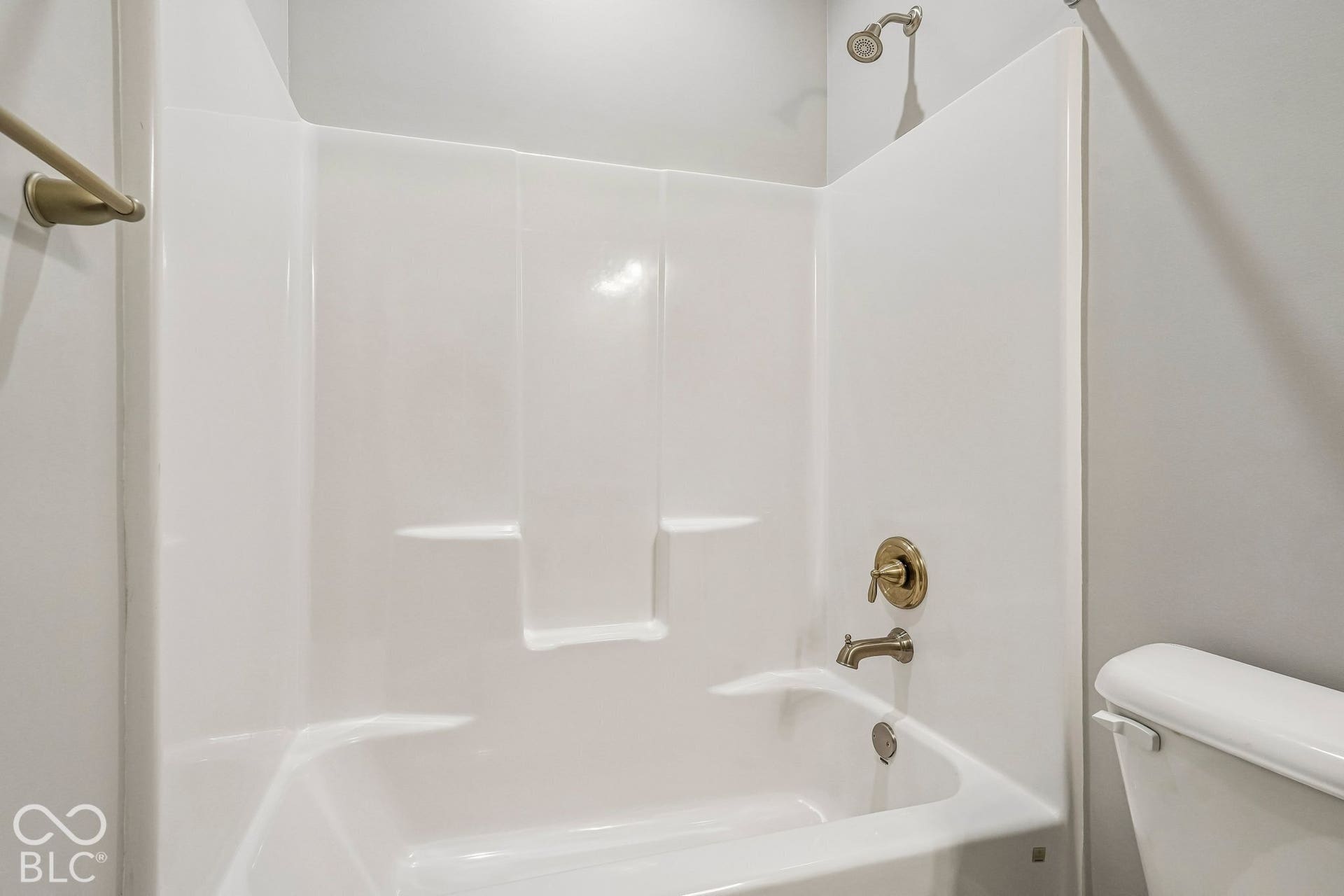 Bathtub with integrated shower surround, bronze fixtures, and showerhead