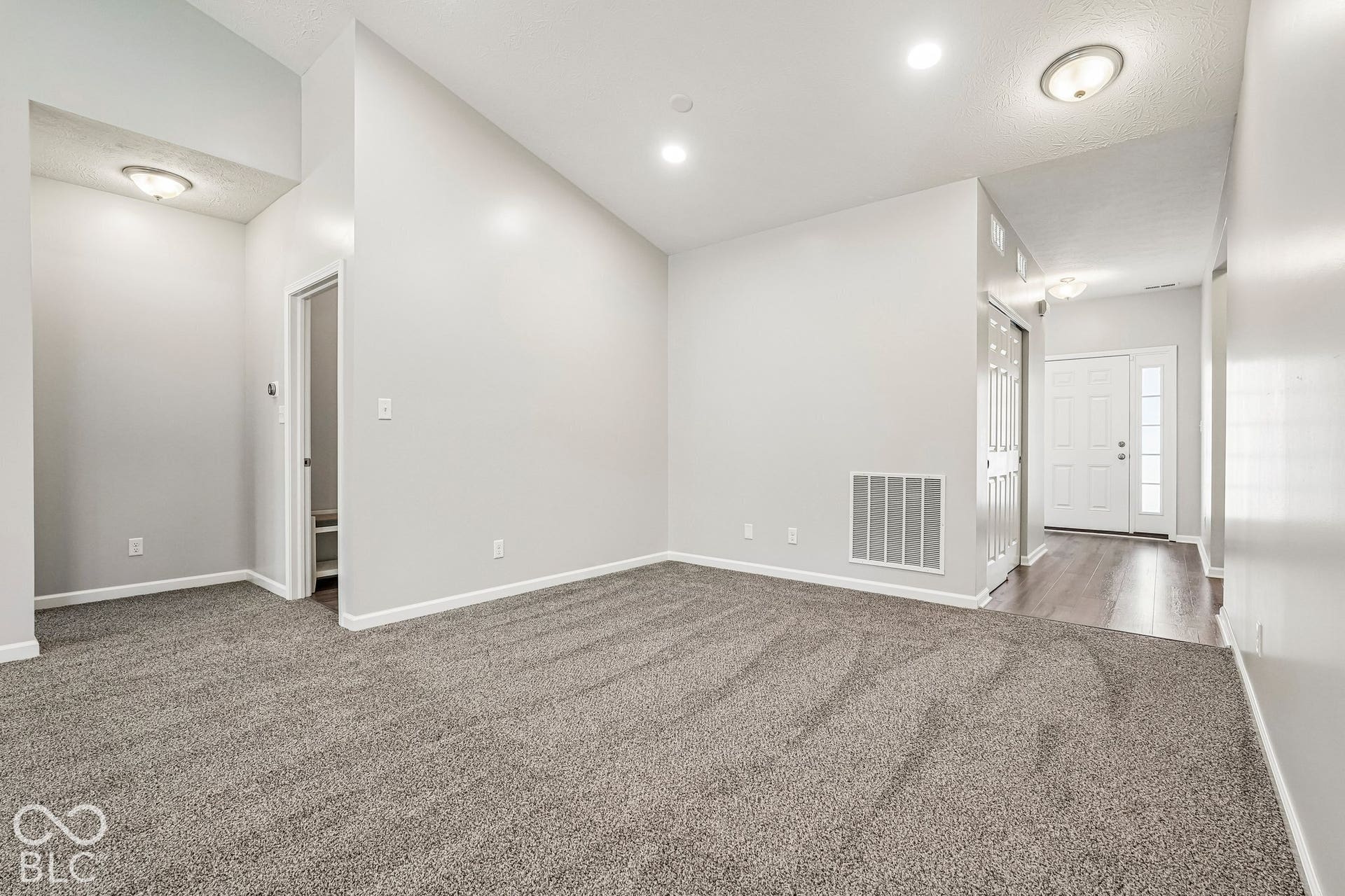 Expansive room featuring vaulted ceilings, recessed lighting, and soft gray carpeting