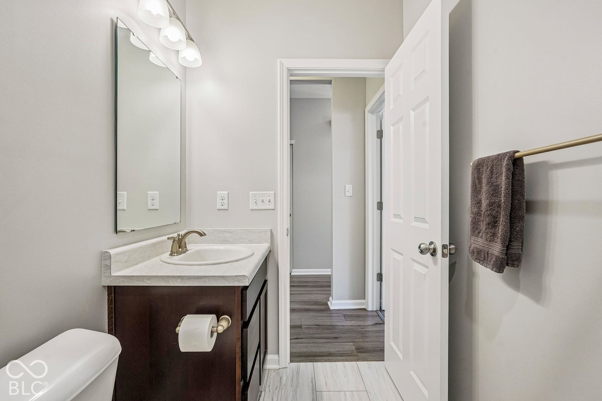 Vanity with integrated sink, brushed nickel faucet, wall-mounted mirror, and overhead light fixture