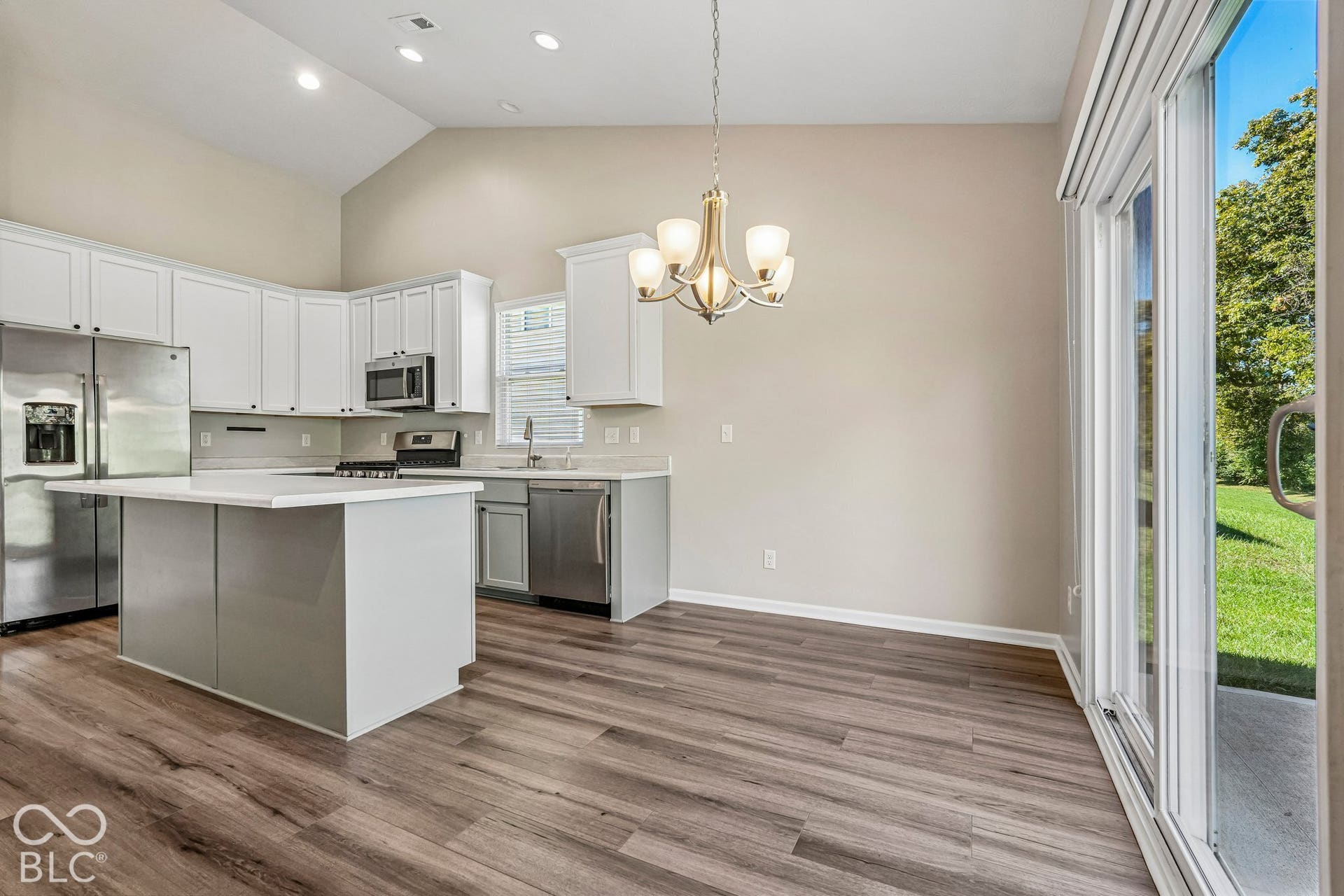 Vaulted ceiling kitchen with white cabinetry and a central island