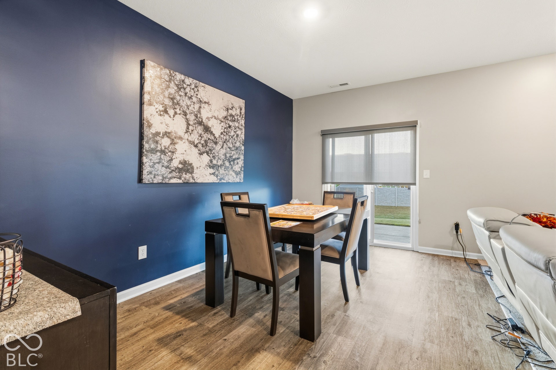 Wood-finish flooring throughout, with a contrasting accent wall, ceiling-mounted lighting, and a sliding glass door with a privacy shade