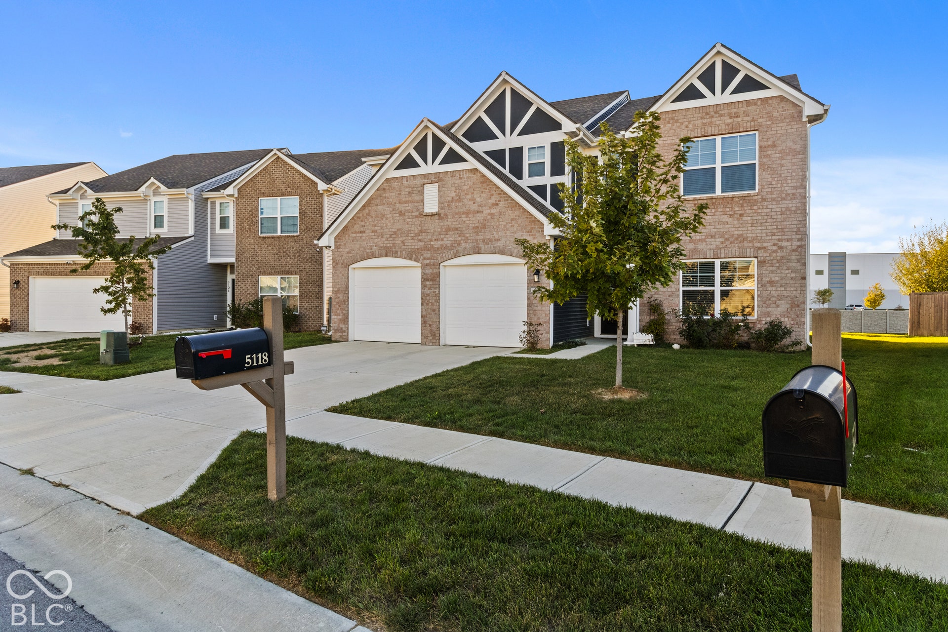 Two-story brick and siding construction with a two-car garage, concrete driveway, and front lawn