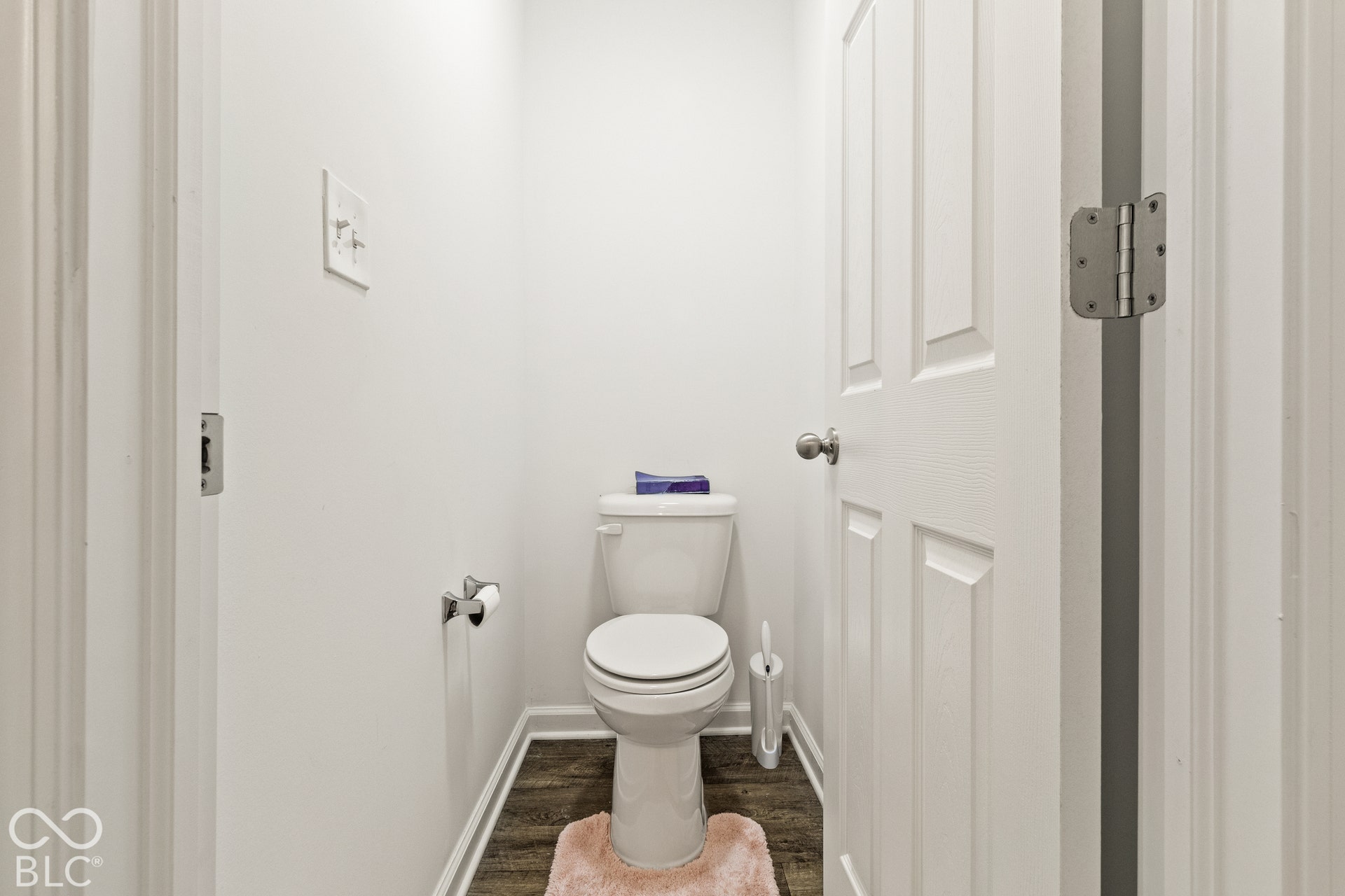 White toilet with wood-finish flooring