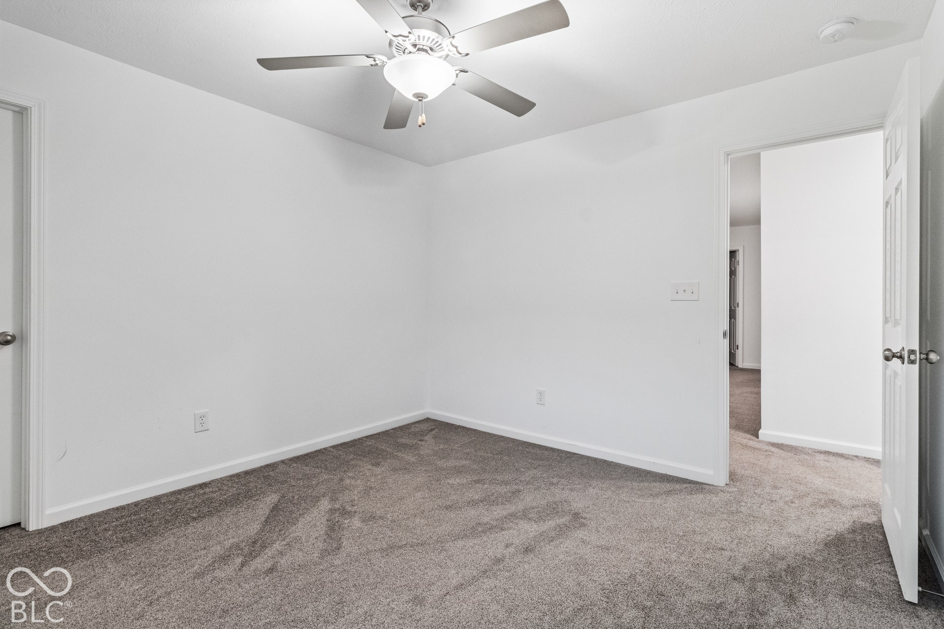 Ceiling fan with integrated lighting, neutral carpet, white walls, white trim, and white interior doors