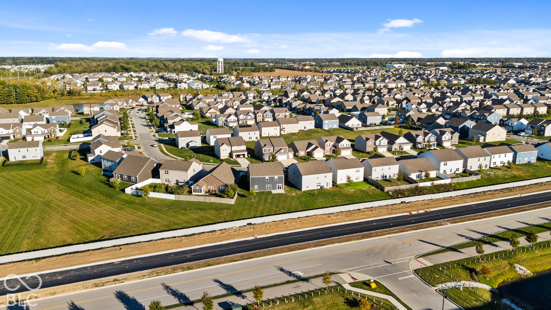 Expansive residential community featuring a variety of home styles, newly constructed roads, and a water tower in the distance