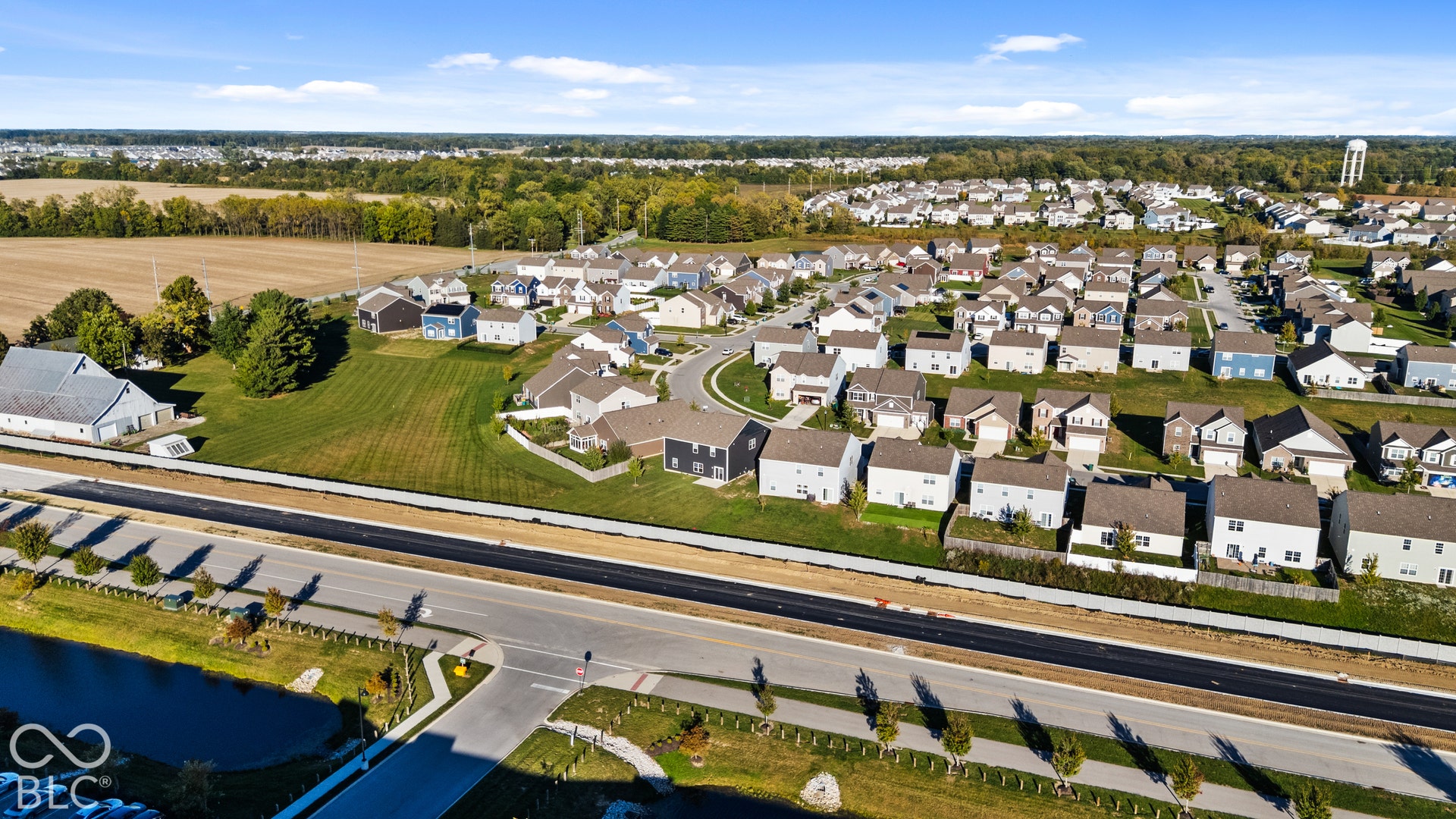 Expansive residential development with numerous single-family homes, surrounding green spaces, and a nearby water tower