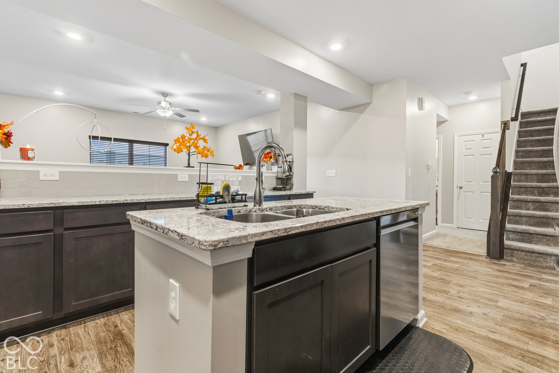 Kitchen island featuring a double-basin sink, granite-style countertop, and stainless steel dishwasher