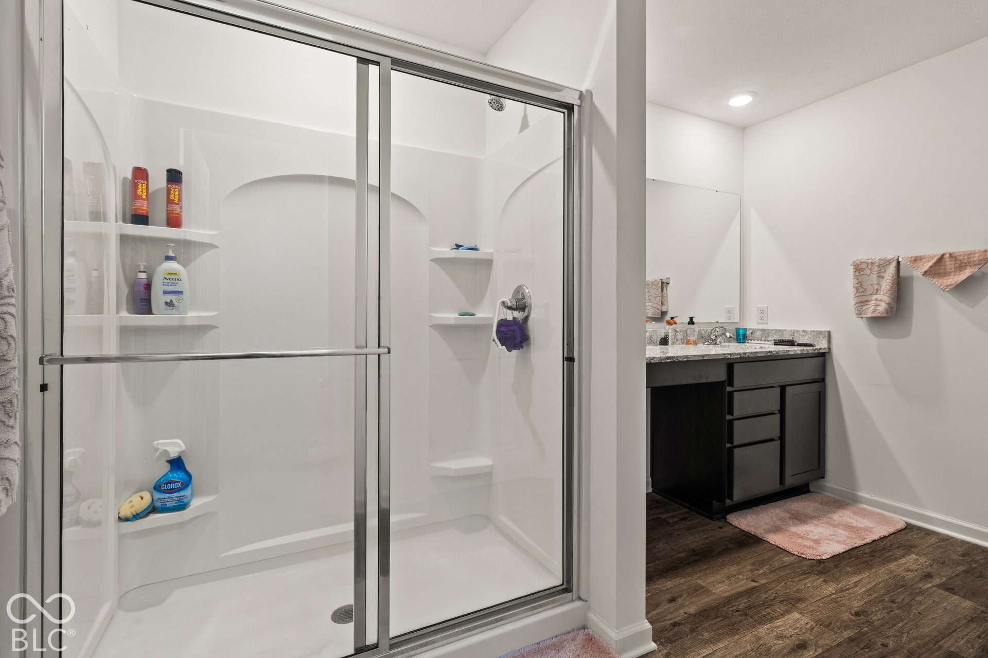 White shower enclosure with clear glass sliding doors and integrated shelving