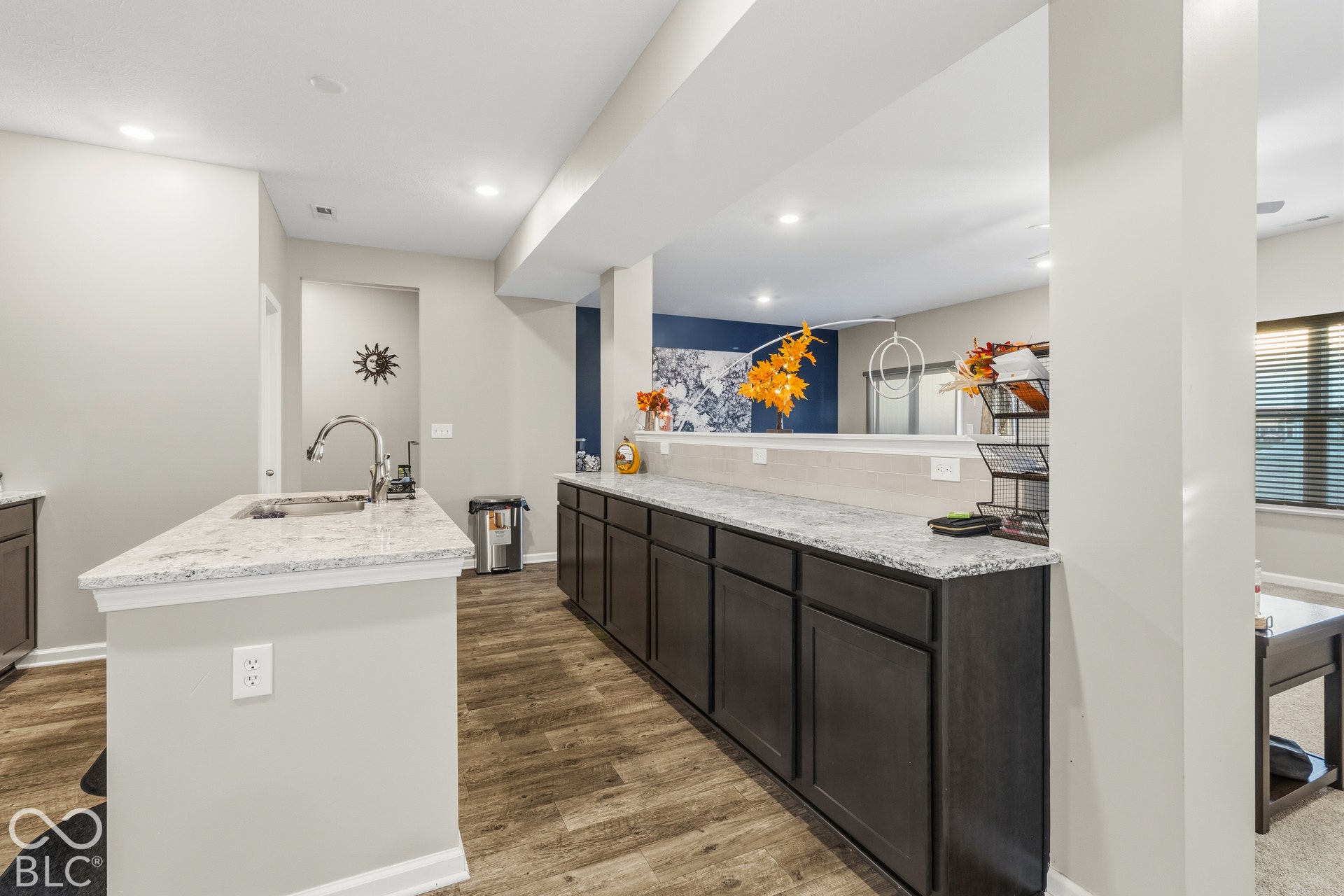Kitchen featuring wood-finish flooring, recessed lighting, a kitchen island with an undermount sink, and light-toned quartz countertops