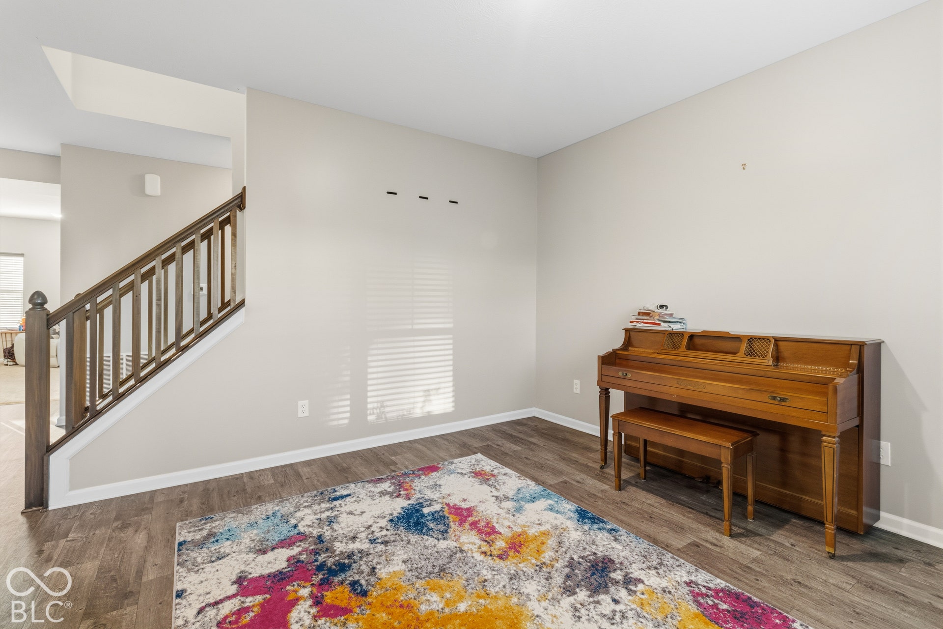 Wood-finish flooring, staircase with wood banister and balusters, and neutral wall paint