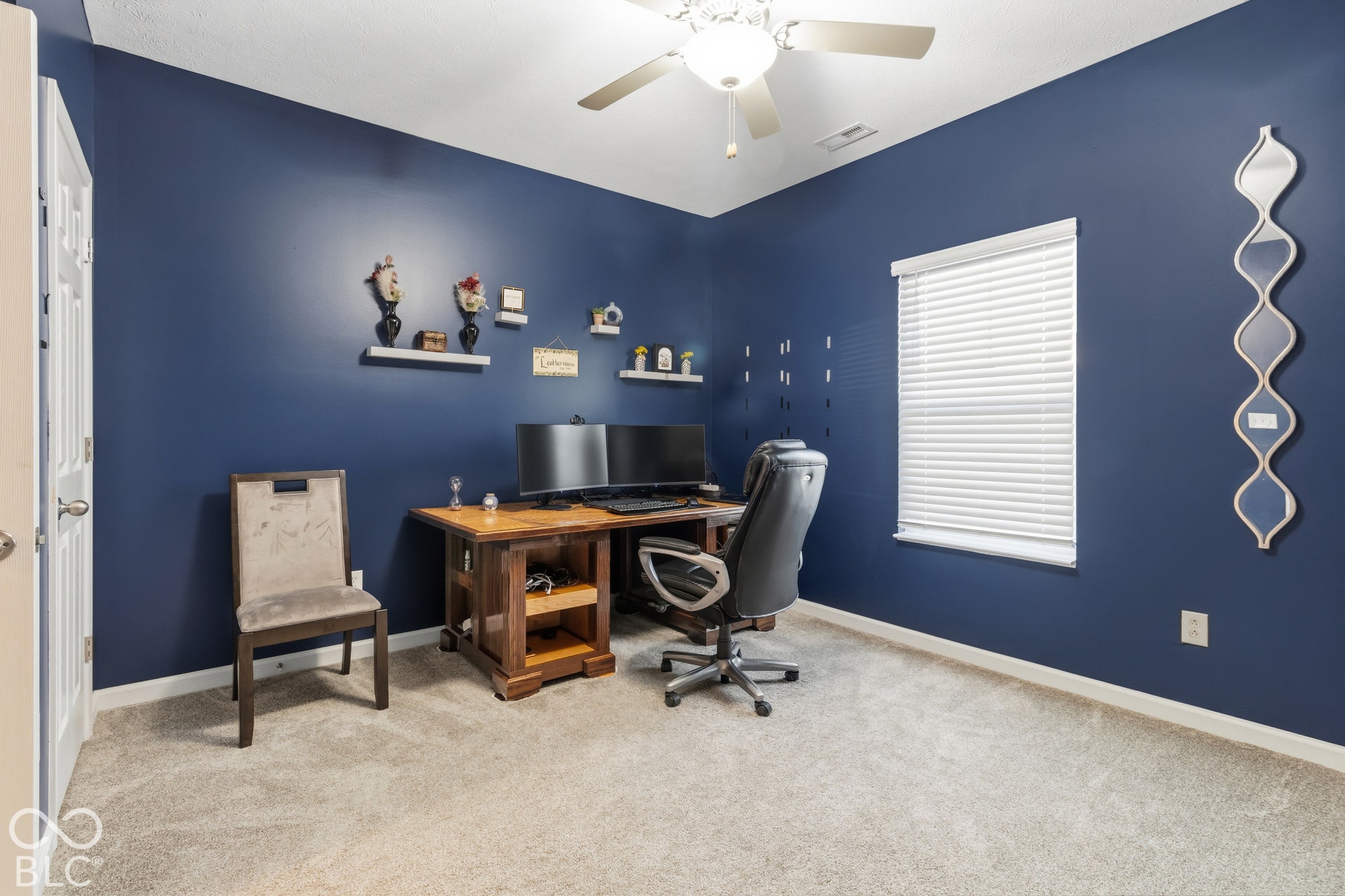 Carpeted room with a ceiling fan, window with blinds, and built-in floating shelves