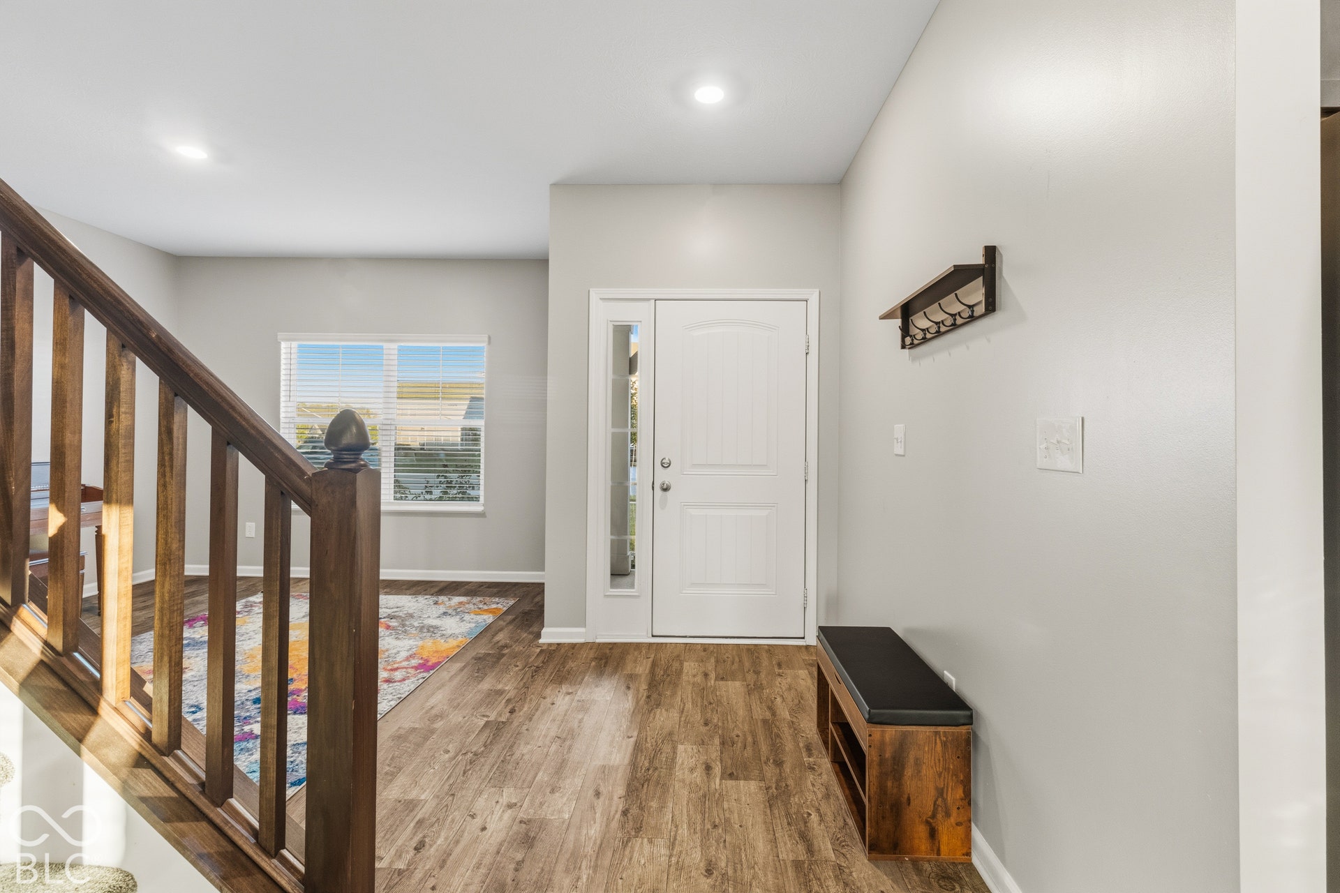 Foyer with wood-finish flooring, white door with sidelight, and wood staircase