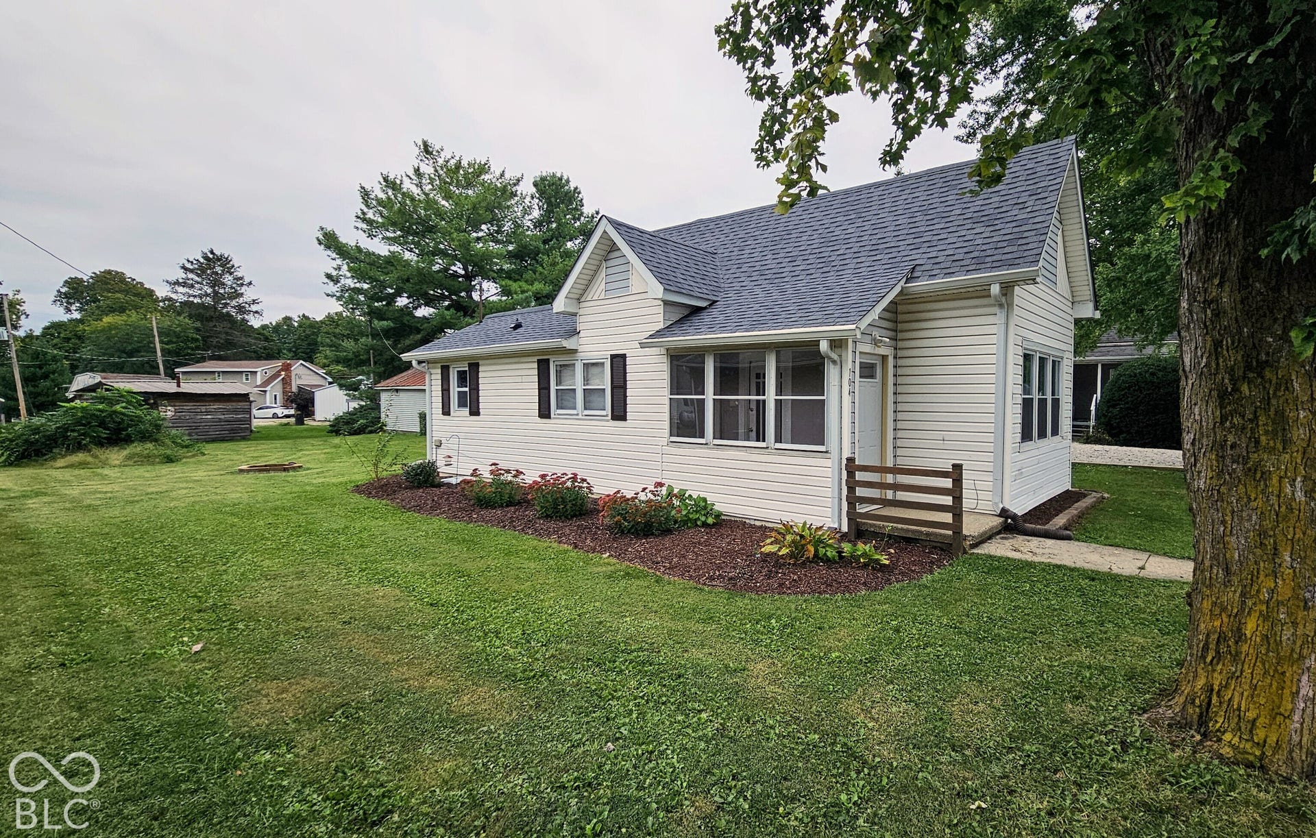 104 E State Street, New Ross, IN 47968 White siding exterior with dark shutters, gabled roofline, and a covered porch with a wood railing
