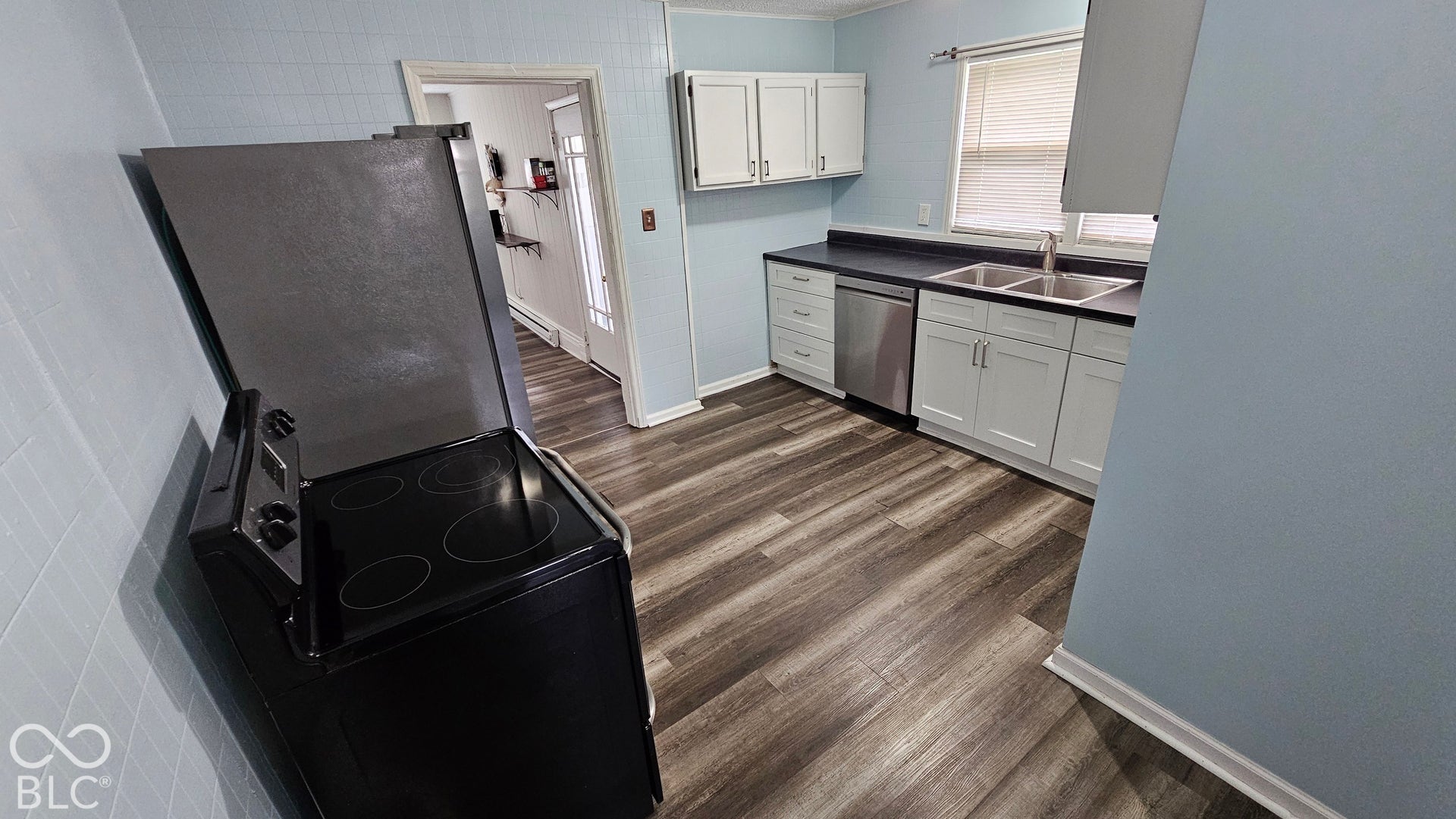 104 E State Street, New Ross, IN 47968 Wood-finish flooring, white cabinetry, dark countertops, stainless steel sink, and a modern black range