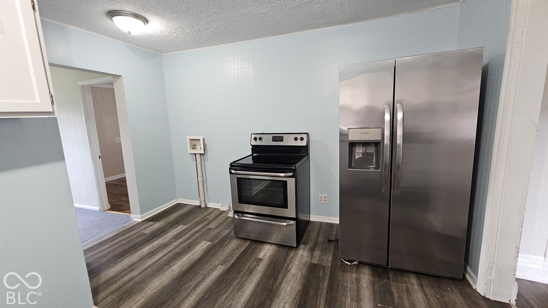 104 E State Street, New Ross, IN 47968 Stainless steel side-by-side refrigerator, stainless steel range, and wood-finish flooring