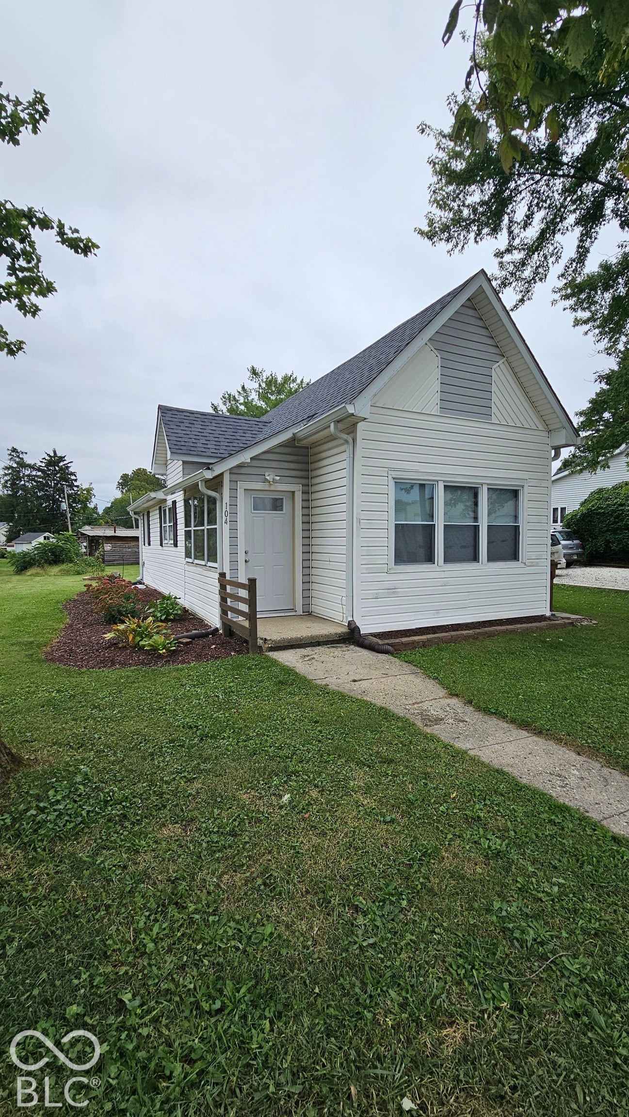 104 E State Street, New Ross, IN 47968 White siding exterior with a dark shingled roof, featuring a gabled dormer and multiple windows