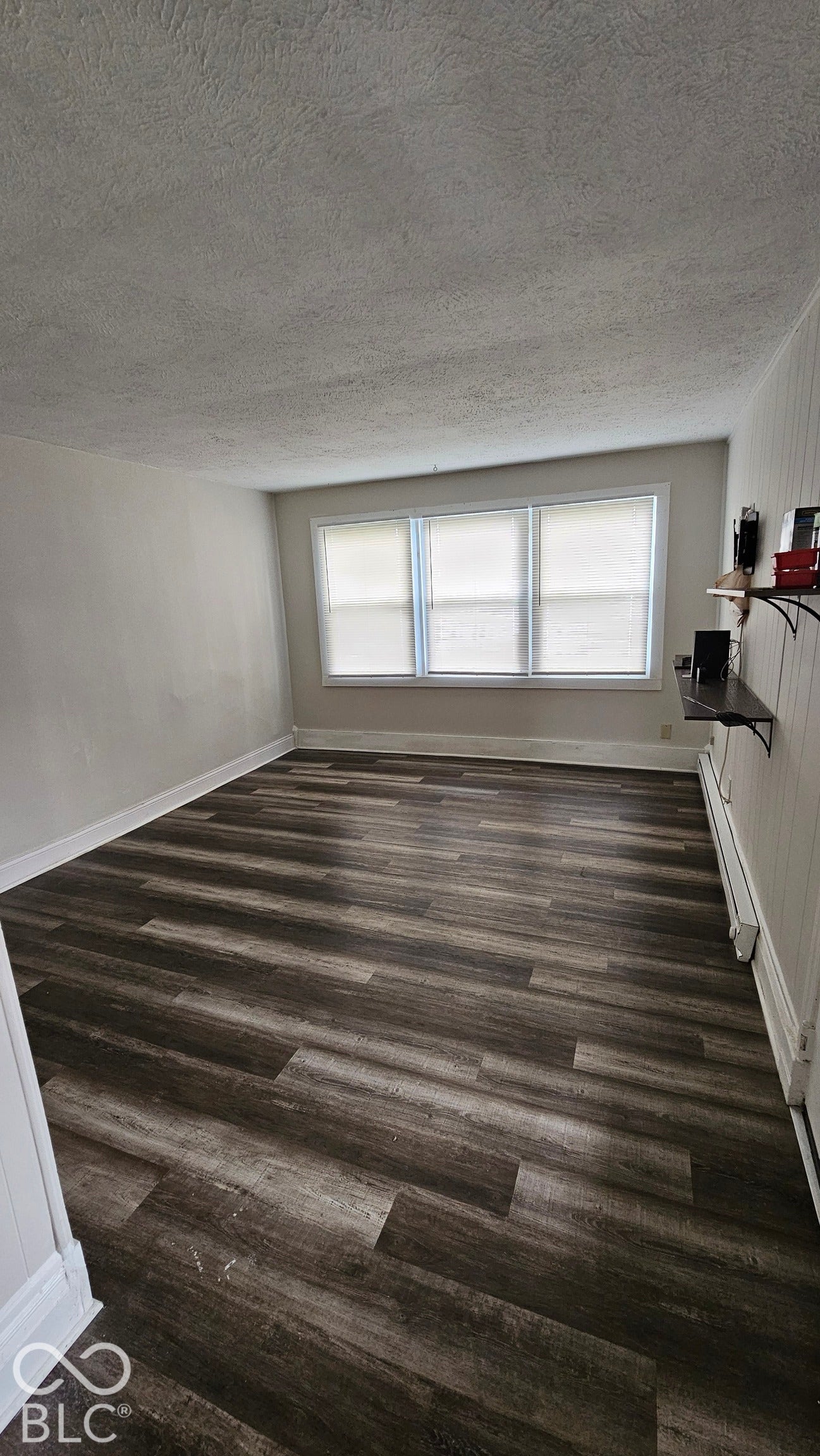 104 E State Street, New Ross, IN 47968 Large windows with blinds, wood-finish flooring, white walls, and a textured ceiling