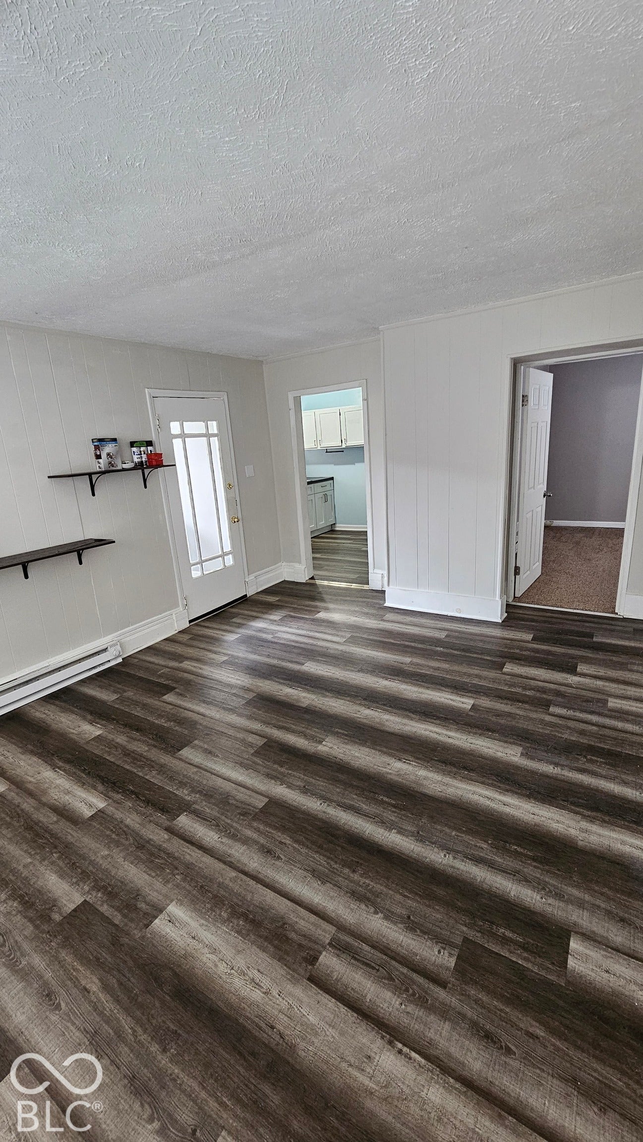 104 E State Street, New Ross, IN 47968 Wood-finish flooring, white paneled walls, white trim, and a door with frosted glass panels