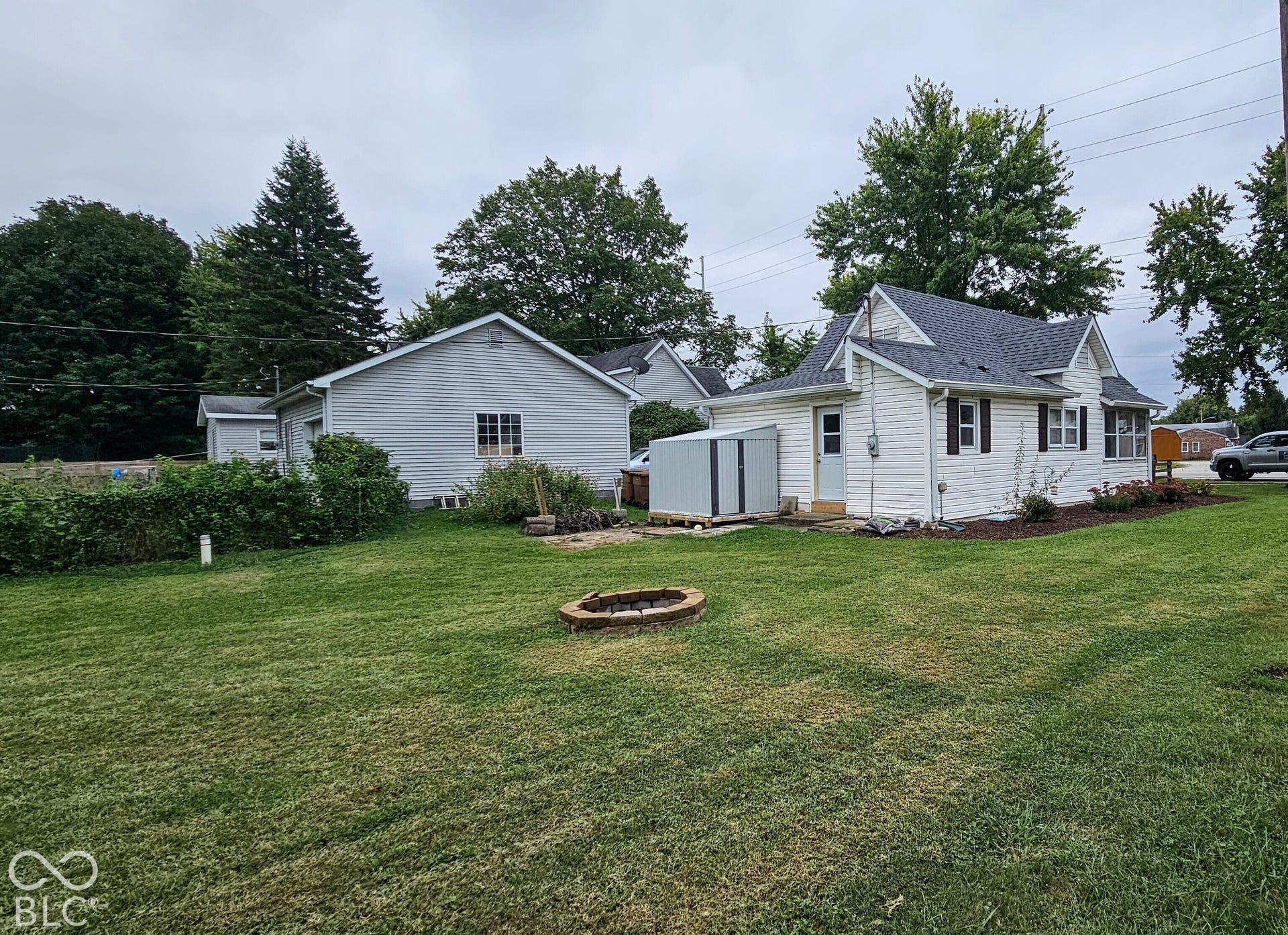 104 E State Street, New Ross, IN 47968 Expansive lawn featuring a fire pit, mature trees, white siding, and dark shutters