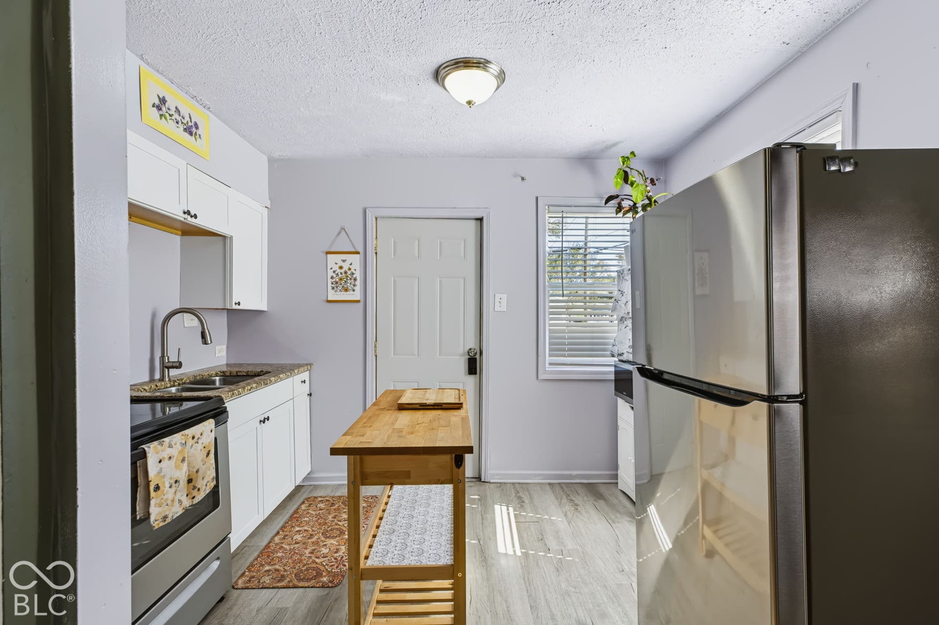 2101 Sharon Avenue, Indianapolis, IN 46222 Kitchen featuring wood-finish flooring, white cabinetry, a stainless steel refrigerator, and a window with blinds