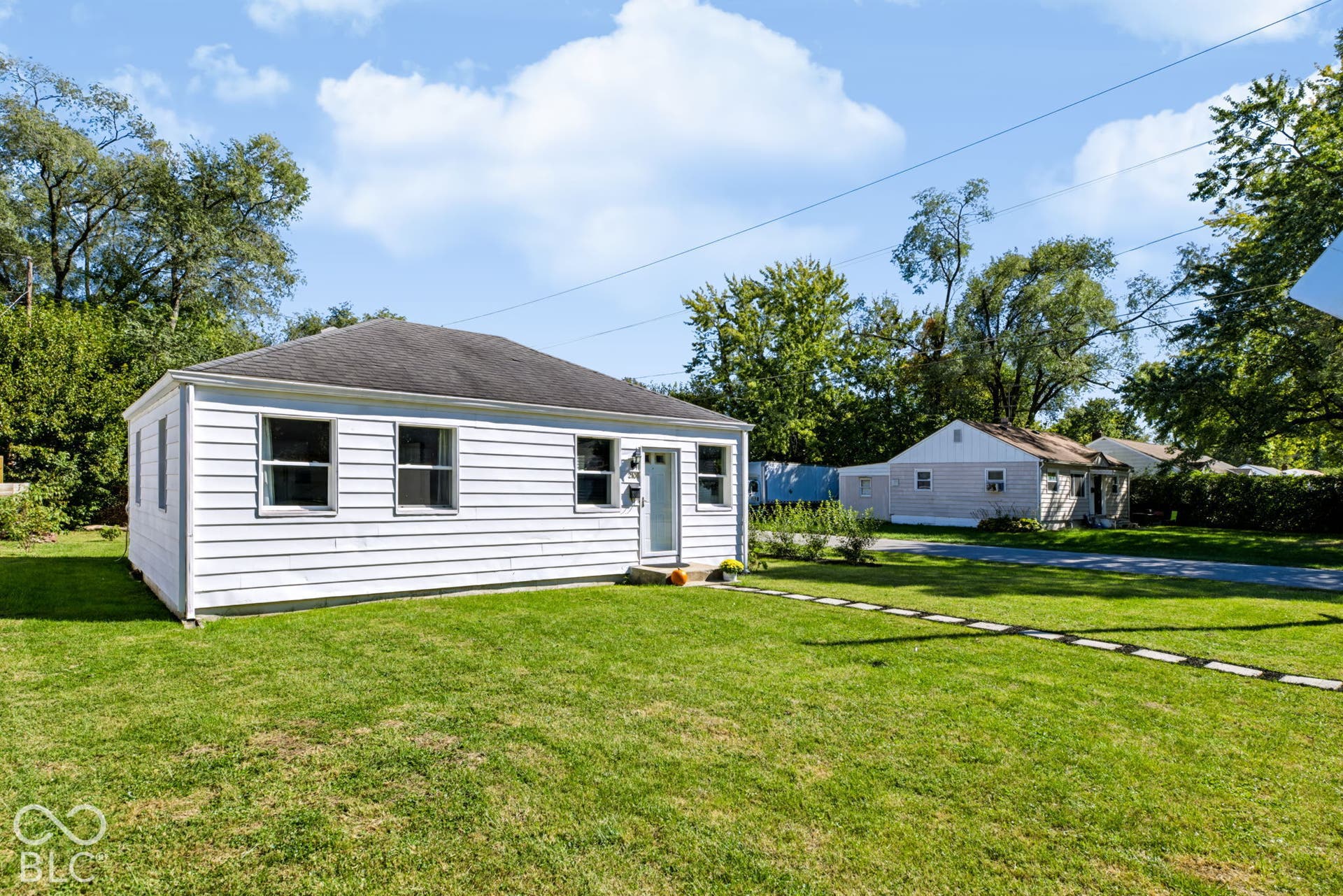 2101 Sharon Avenue, Indianapolis, IN 46222 White siding exterior with a dark shingle roof, multiple windows, and a paved walkway