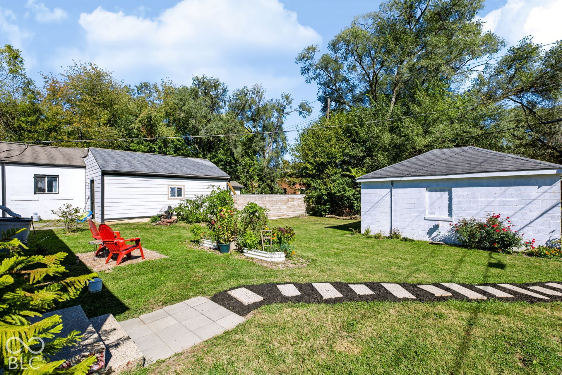 2101 Sharon Avenue, Indianapolis, IN 46222 Expansive backyard featuring a manicured lawn, two detached structures, and a paver pathway