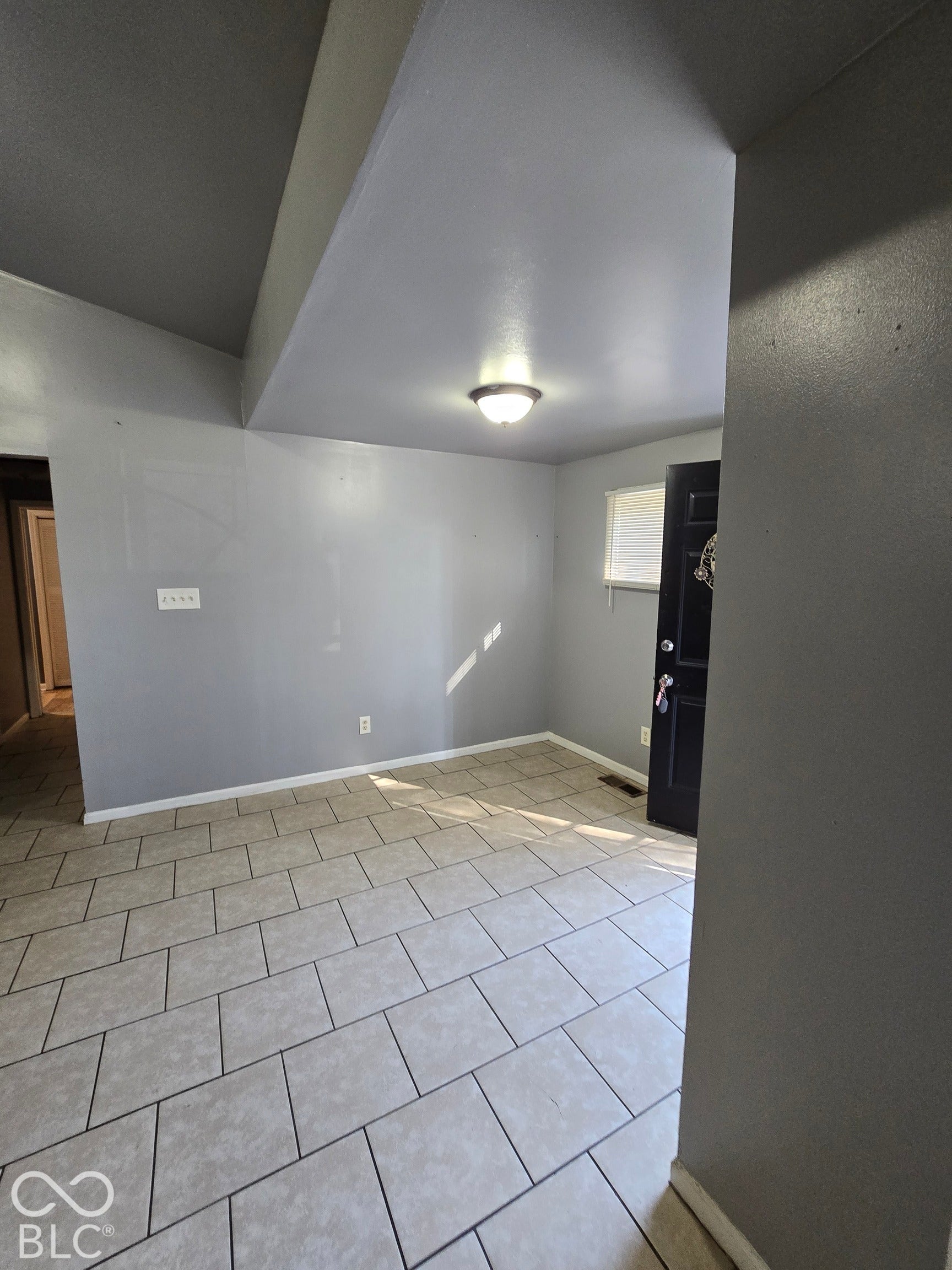 Rectangular tile flooring with dark grout, neutral wall paint, and a semi-flush mount ceiling fixture