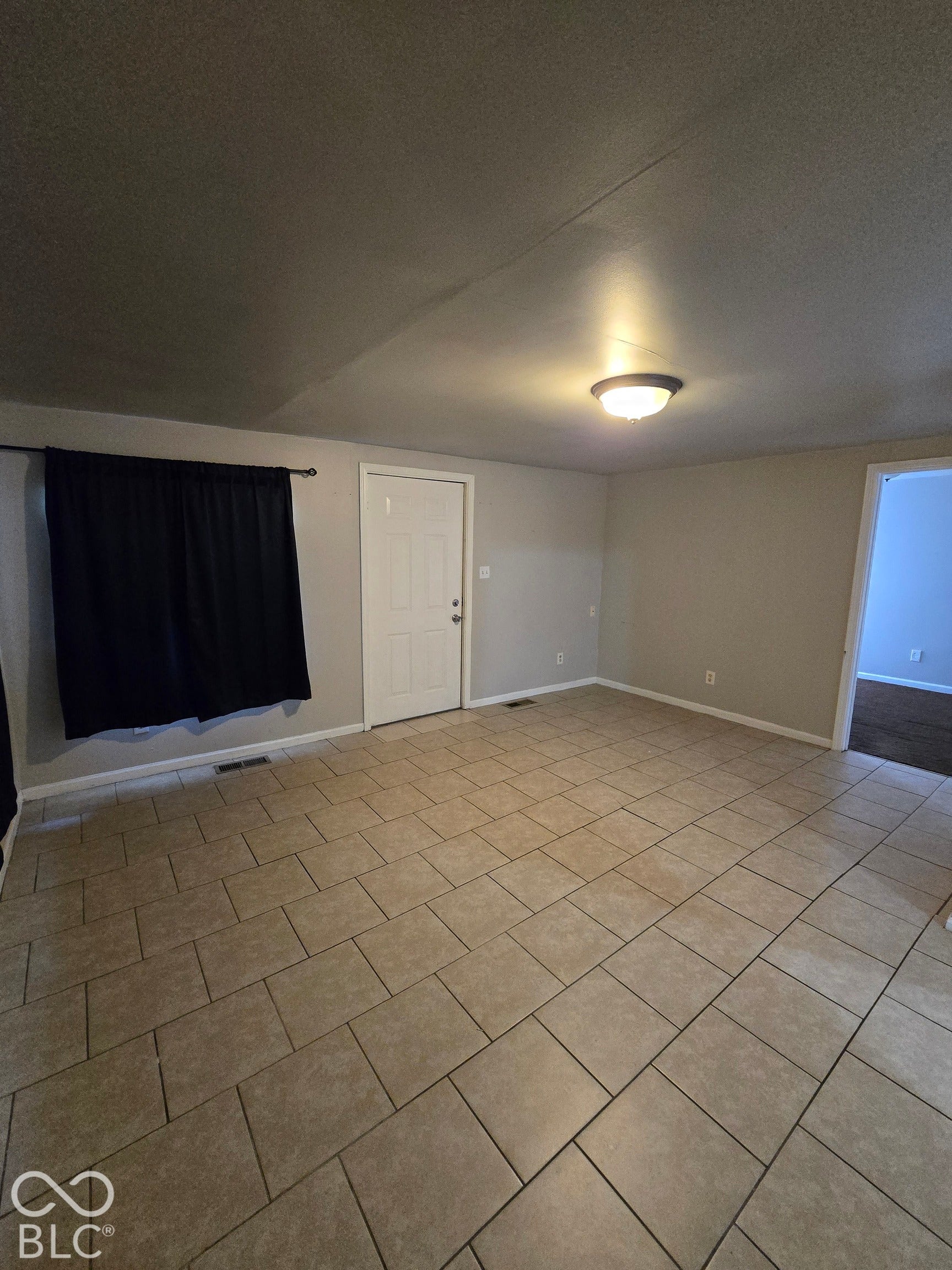 Ceramic tile flooring, neutral wall paint, white interior door, and a flush mount ceiling light fixture