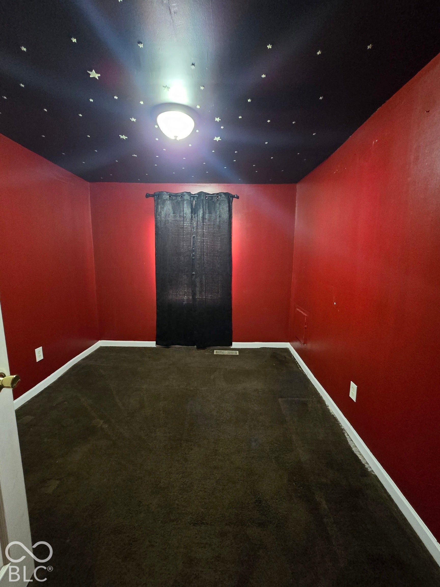 Carpet flooring, deep red walls, and a black ceiling with star decals