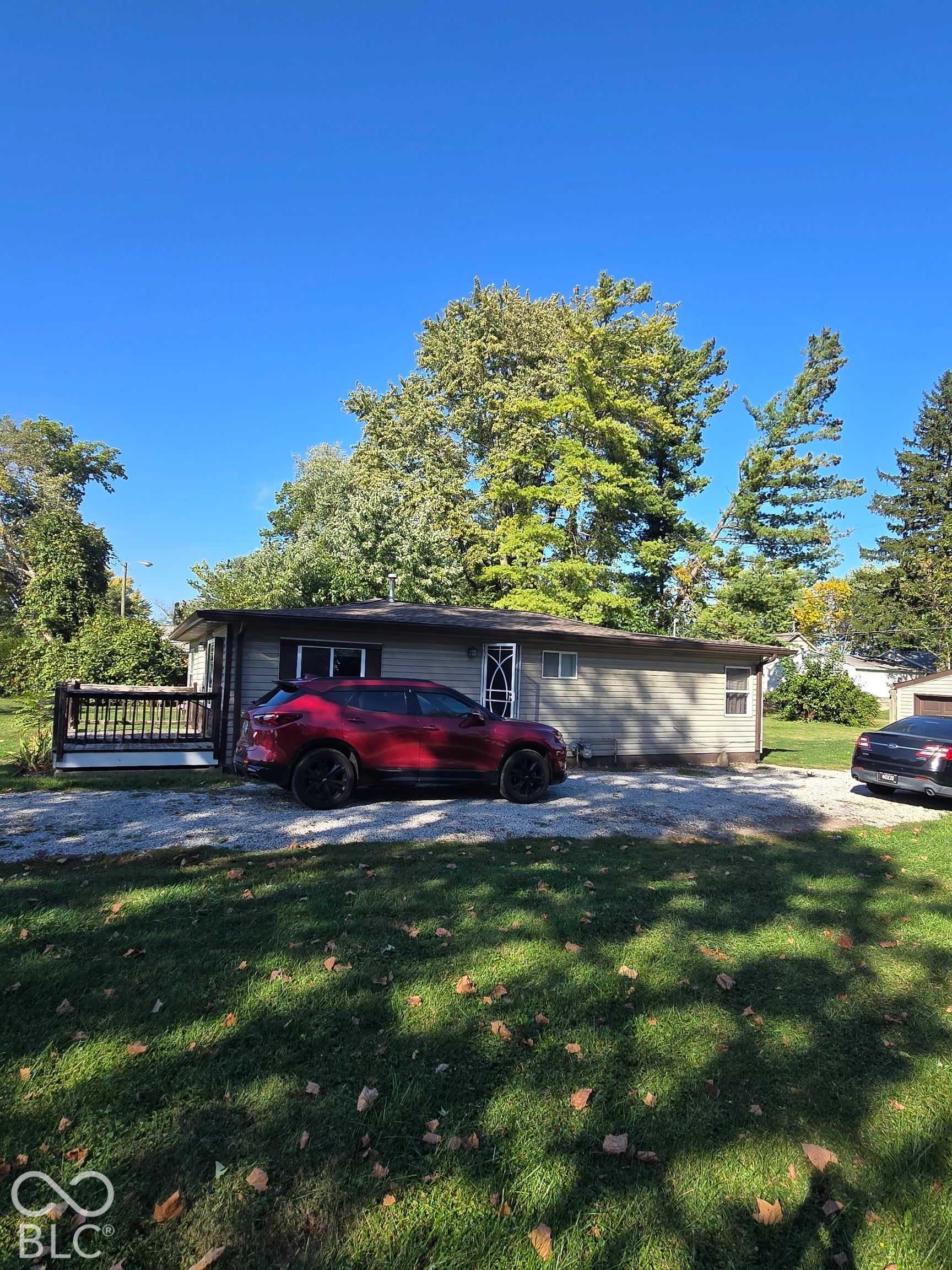 Single-story residence with horizontal siding, gravel driveway, and a wood-slat deck