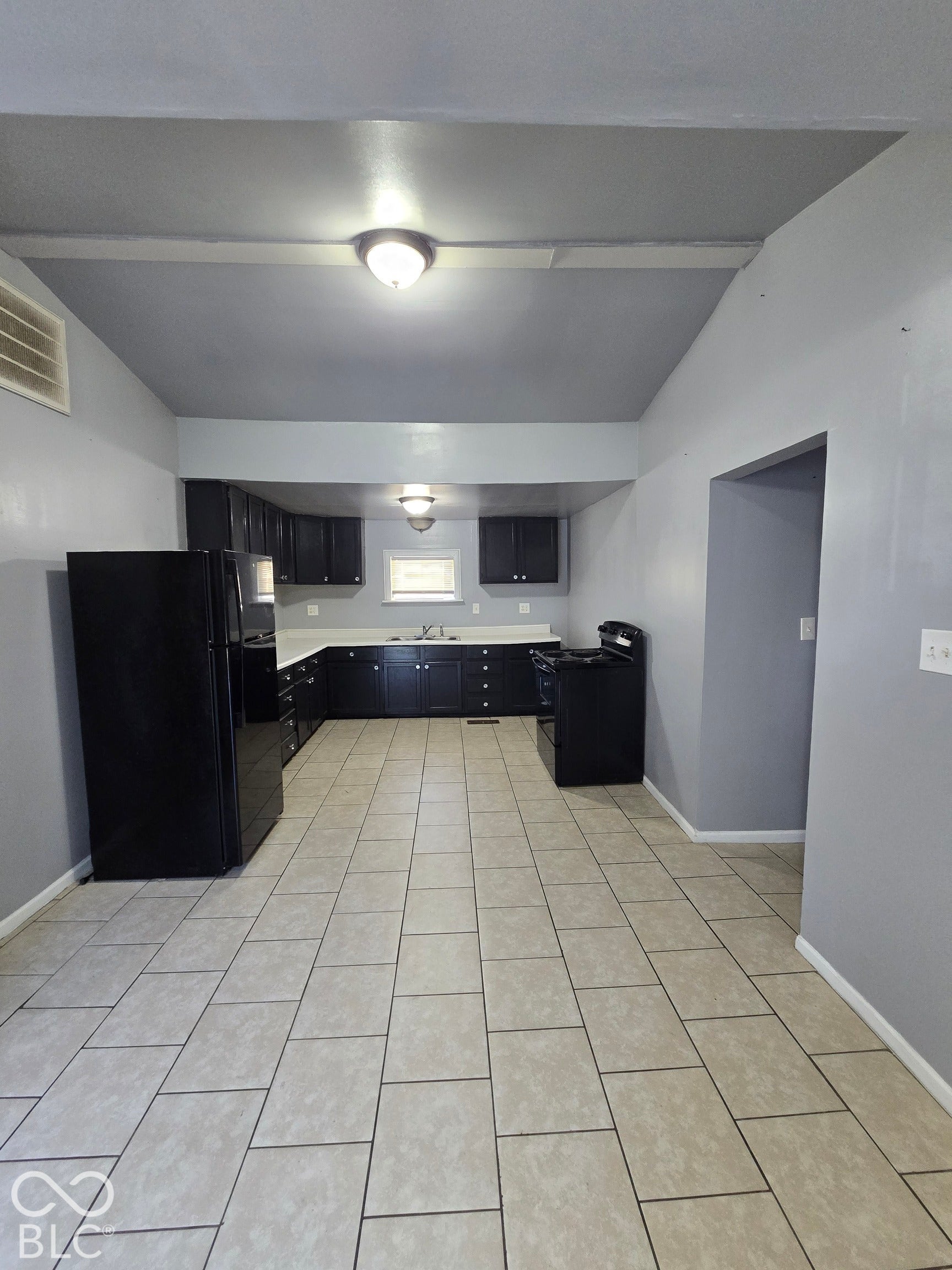 Spacious kitchen featuring tile flooring, dark cabinetry, and white countertops