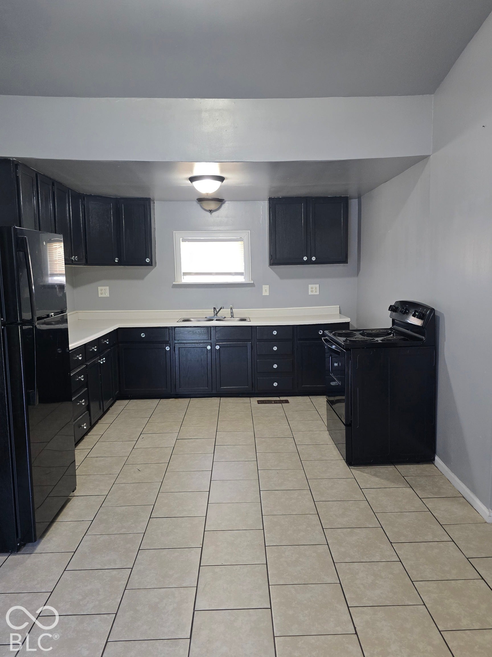 Kitchen featuring black cabinetry, white countertops, tile flooring, and integrated black appliances
