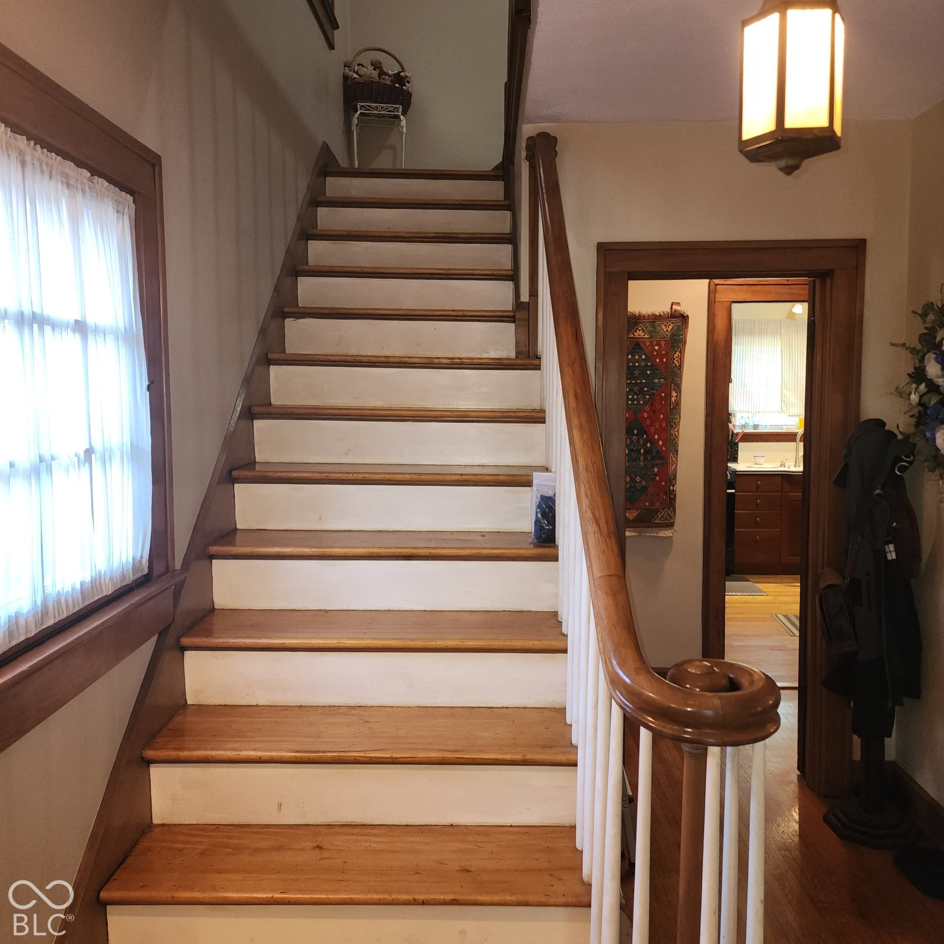 Wood-finish staircase with white risers and balusters, featuring a carved wood handrail