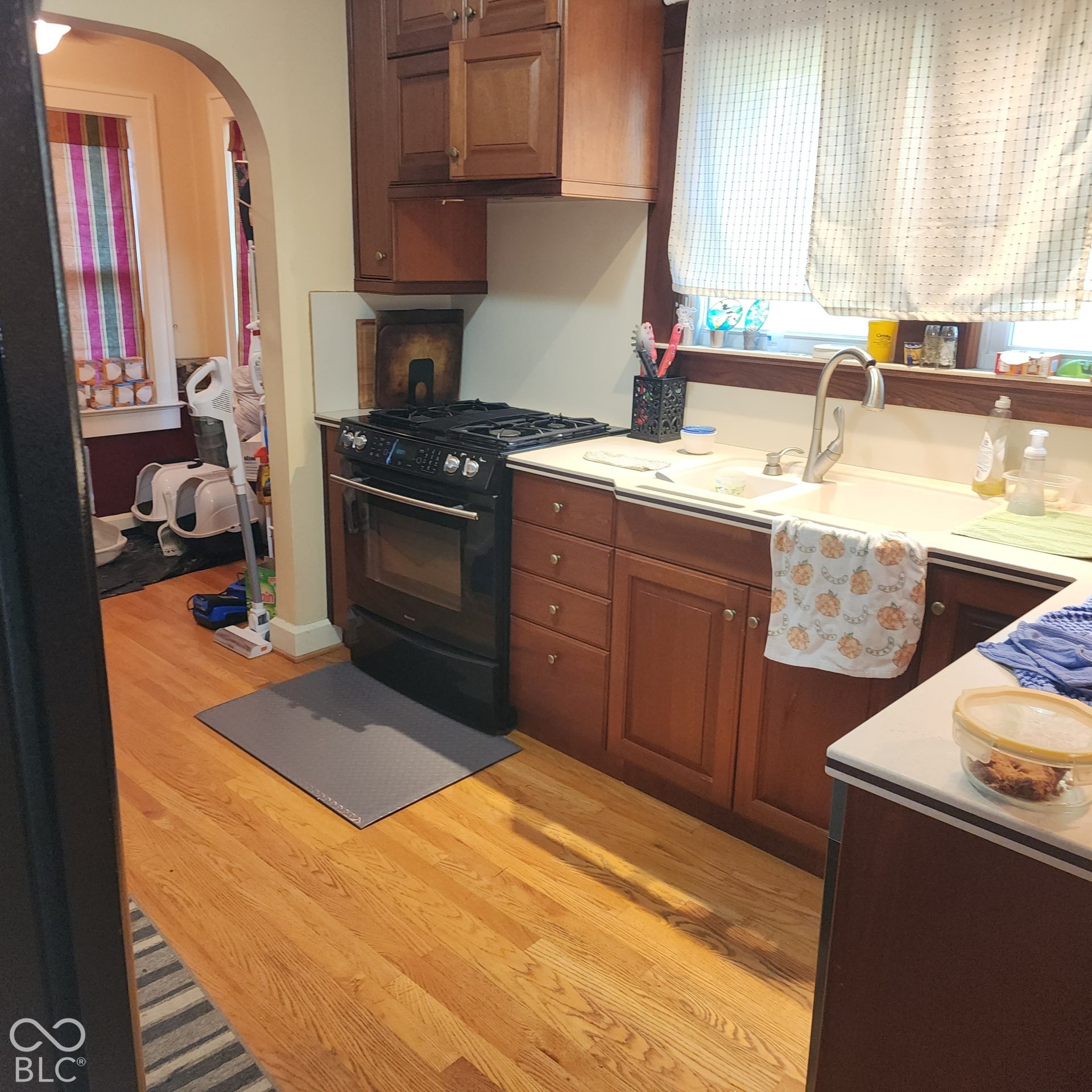 Hardwood flooring, wood cabinetry, built-in gas range, integrated sink, and white countertops