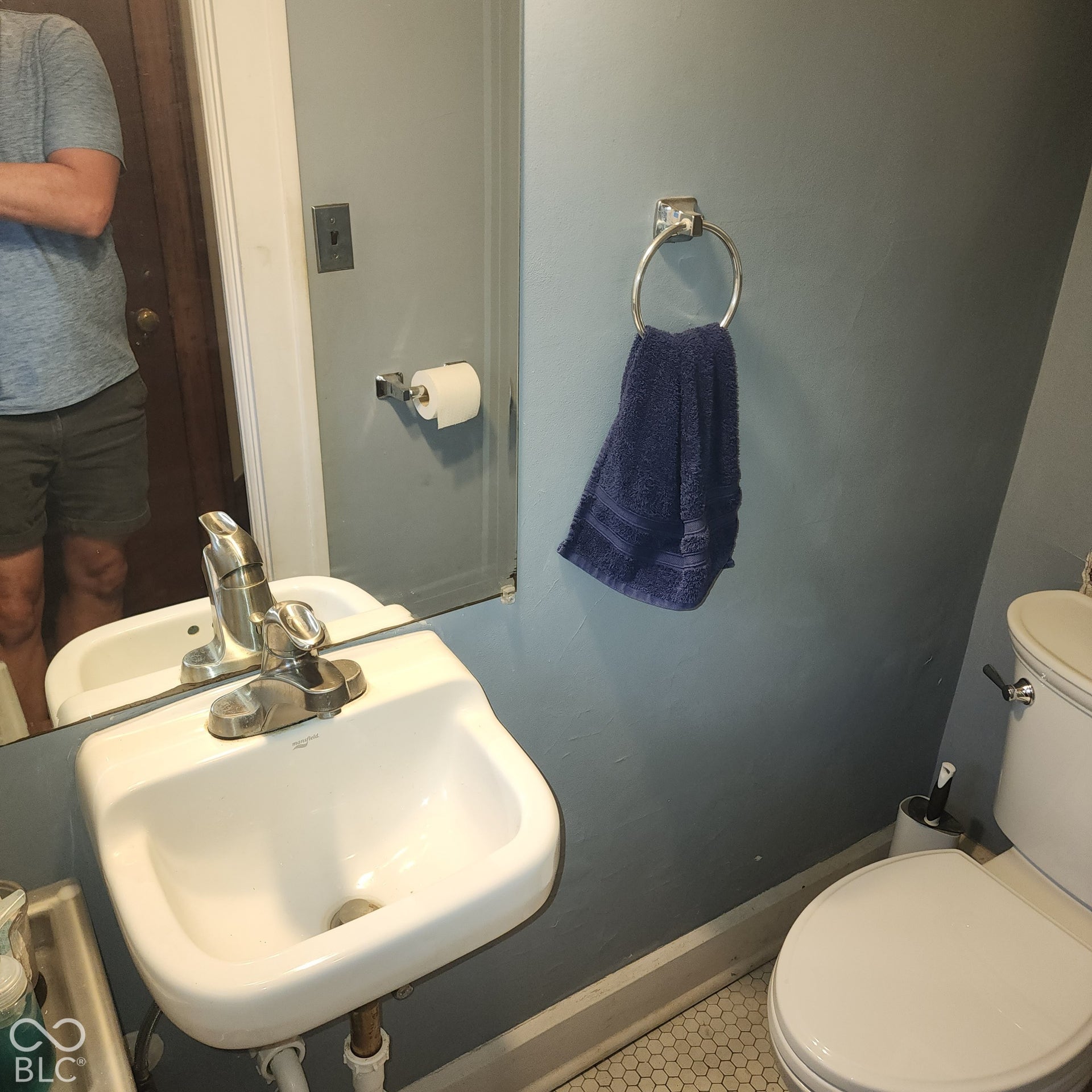 Wall-mounted sink with a chrome faucet, adjacent to a toilet with a white tank