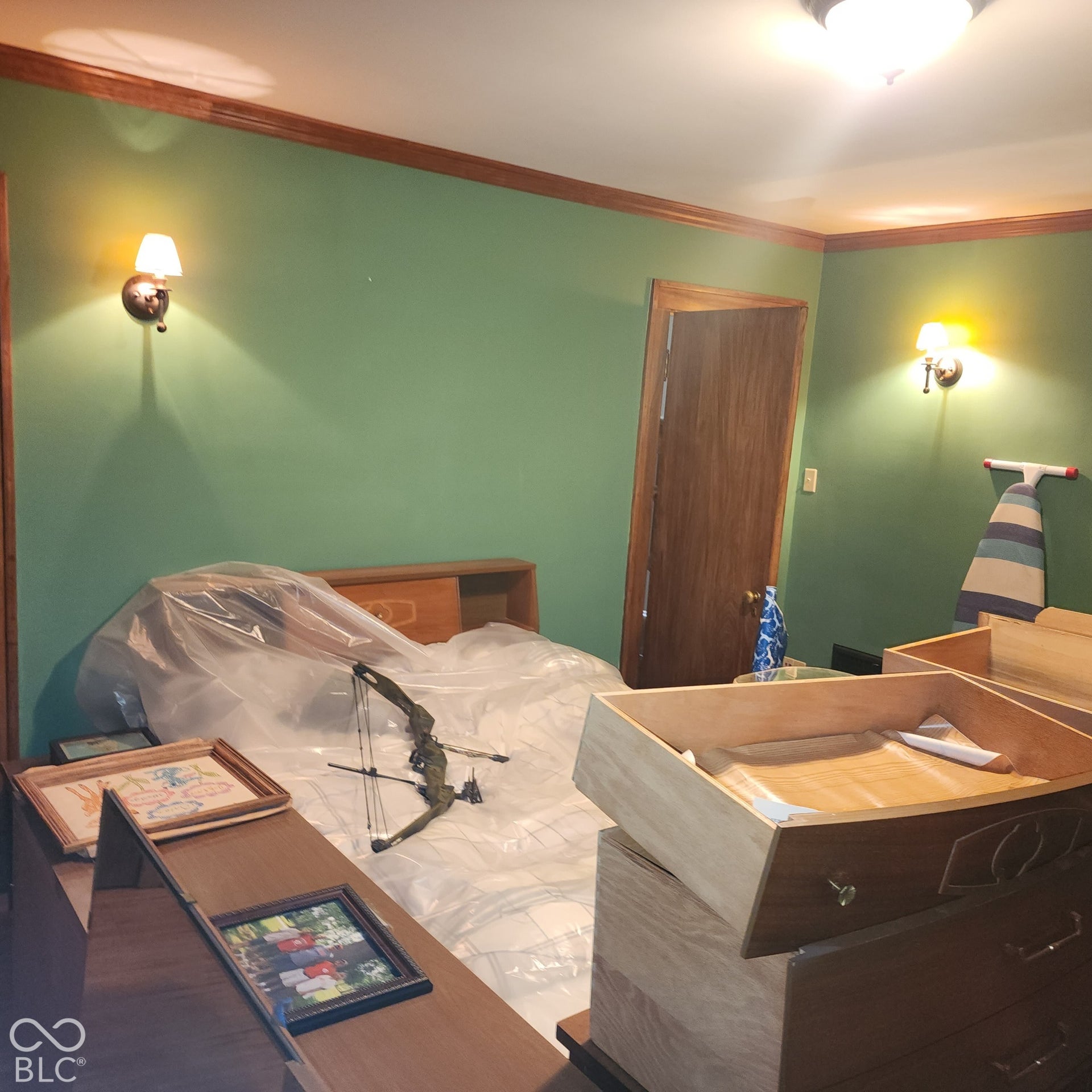 Green painted walls with wood trim, wood-finish interior door, and dual wall sconces