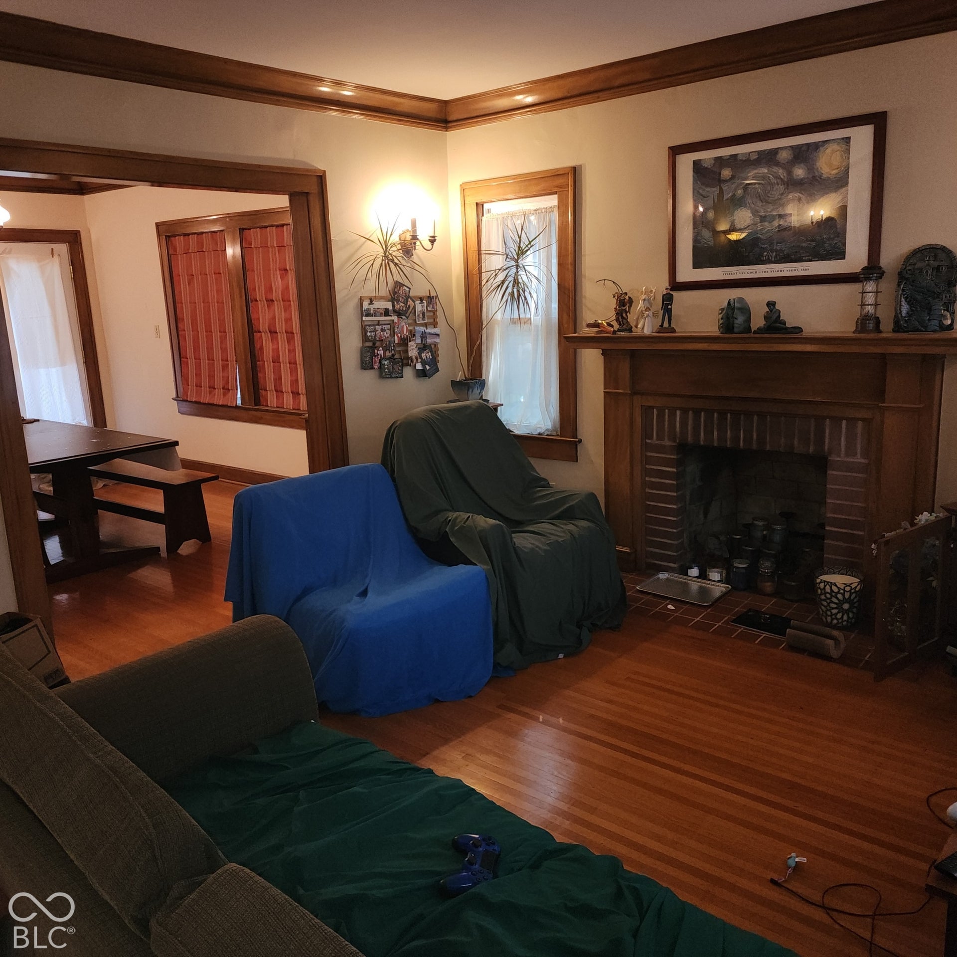 Wood-finish flooring throughout, brick fireplace with wood mantel, wood-trimmed windows, and wood-trimmed doorways
