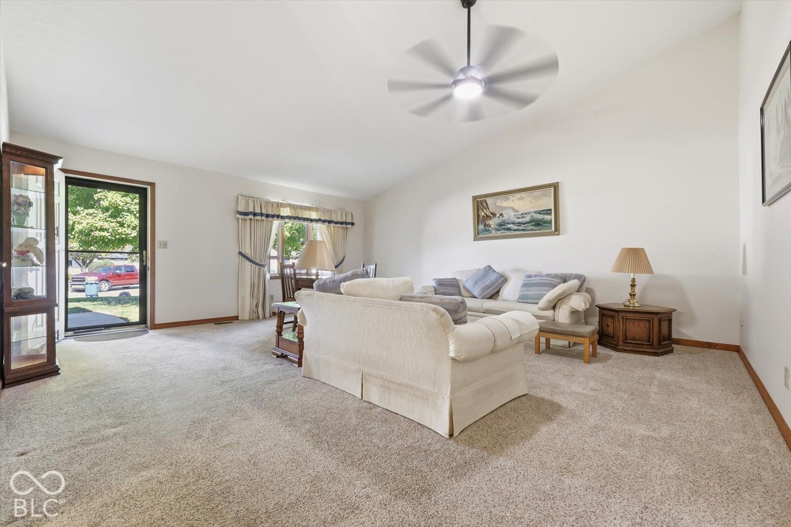 Vaulted ceiling featuring a brand new central lighted ceiling fan, neutral carpeting, and a glass-paned exterior door