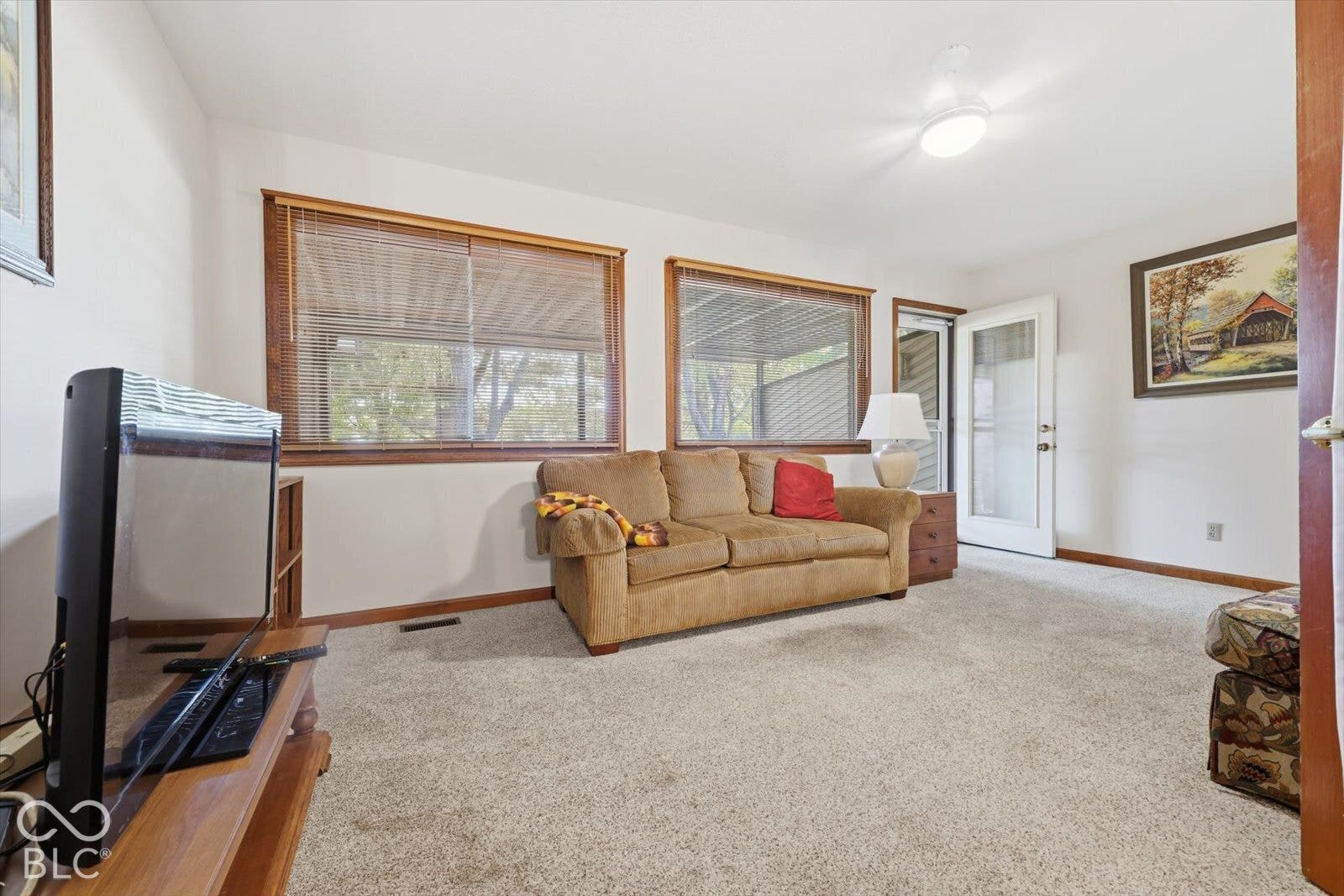 Neutral wall color, carpeted flooring, dual wood-framed windows, and a glass-paneled exterior door