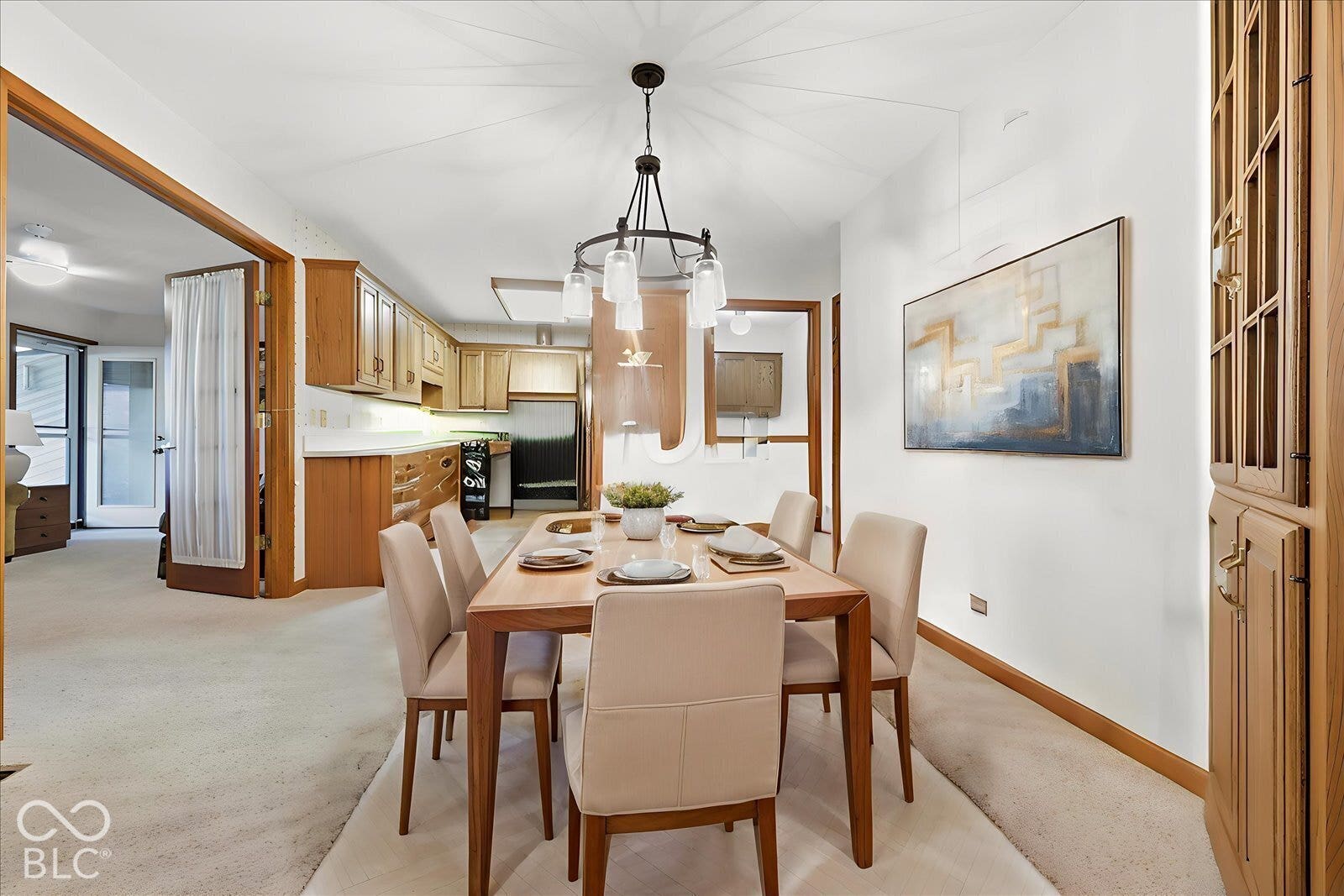 Virtually Altered - Dining area featuring a wood-finished built-in cabinet, new overhead chandelier with glass shades, and neutral wall-to-wall carpeting