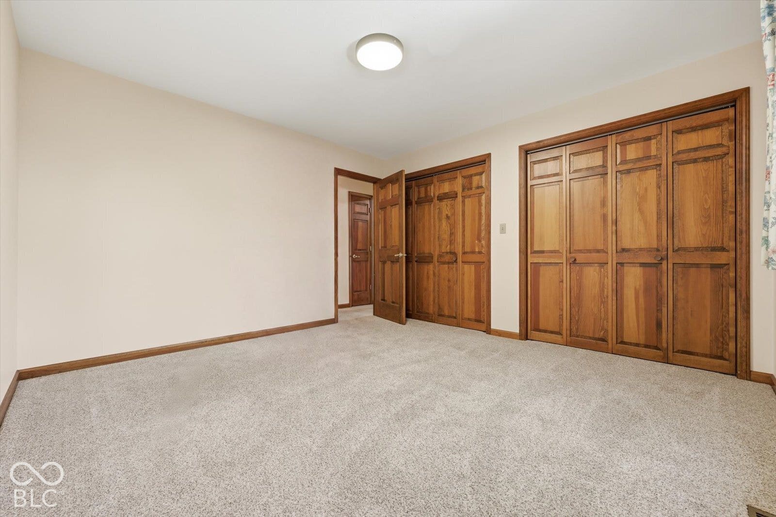 Virtually Altered - Bedroom Two- featuring neutral-toned carpeting, wood-finish bi-fold closet doors, and wood-finish interior doors