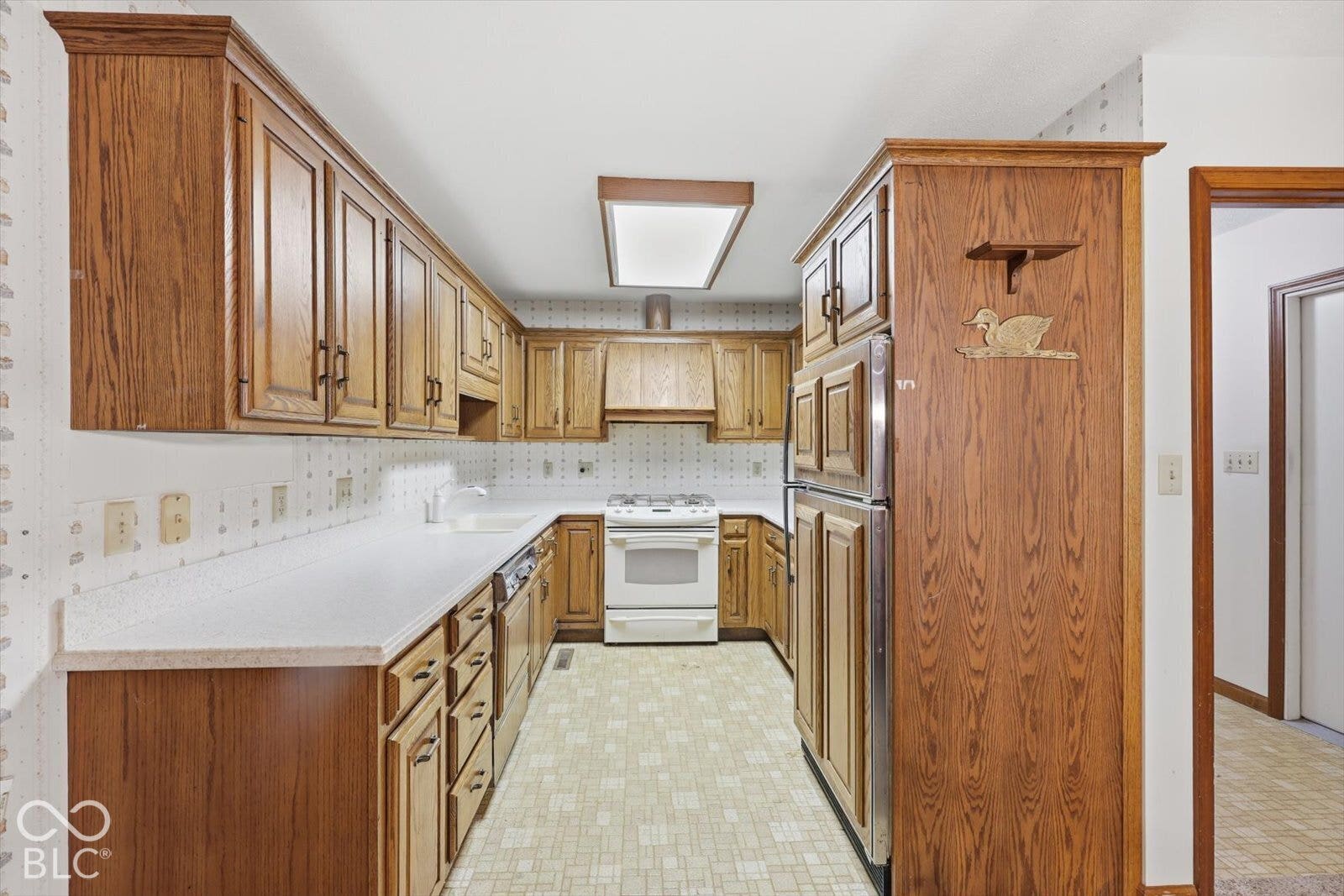 Virtually Altered - Kitchen featuring wood cabinetry, corian countertops, a four-burner gas range, range hood, and a recessed ceiling light fixture