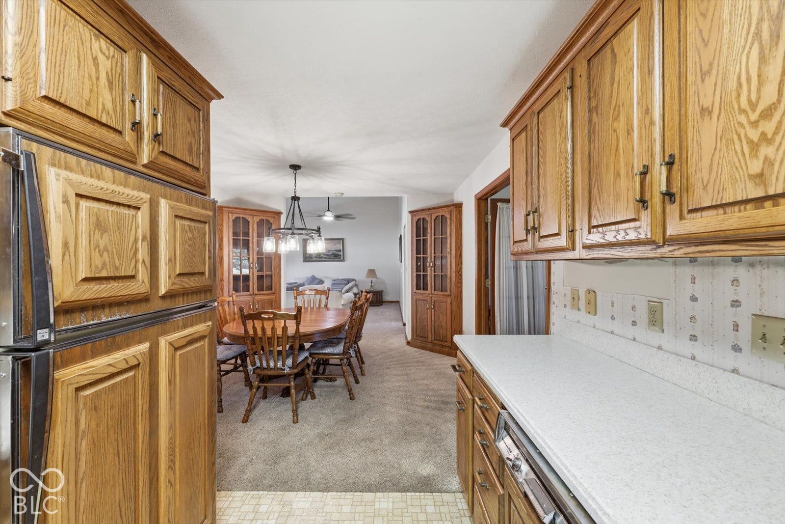 Virtually Altered - Kitchen featuring natural wood cabinetry, corian countertops, and built-in hutch cabinetry