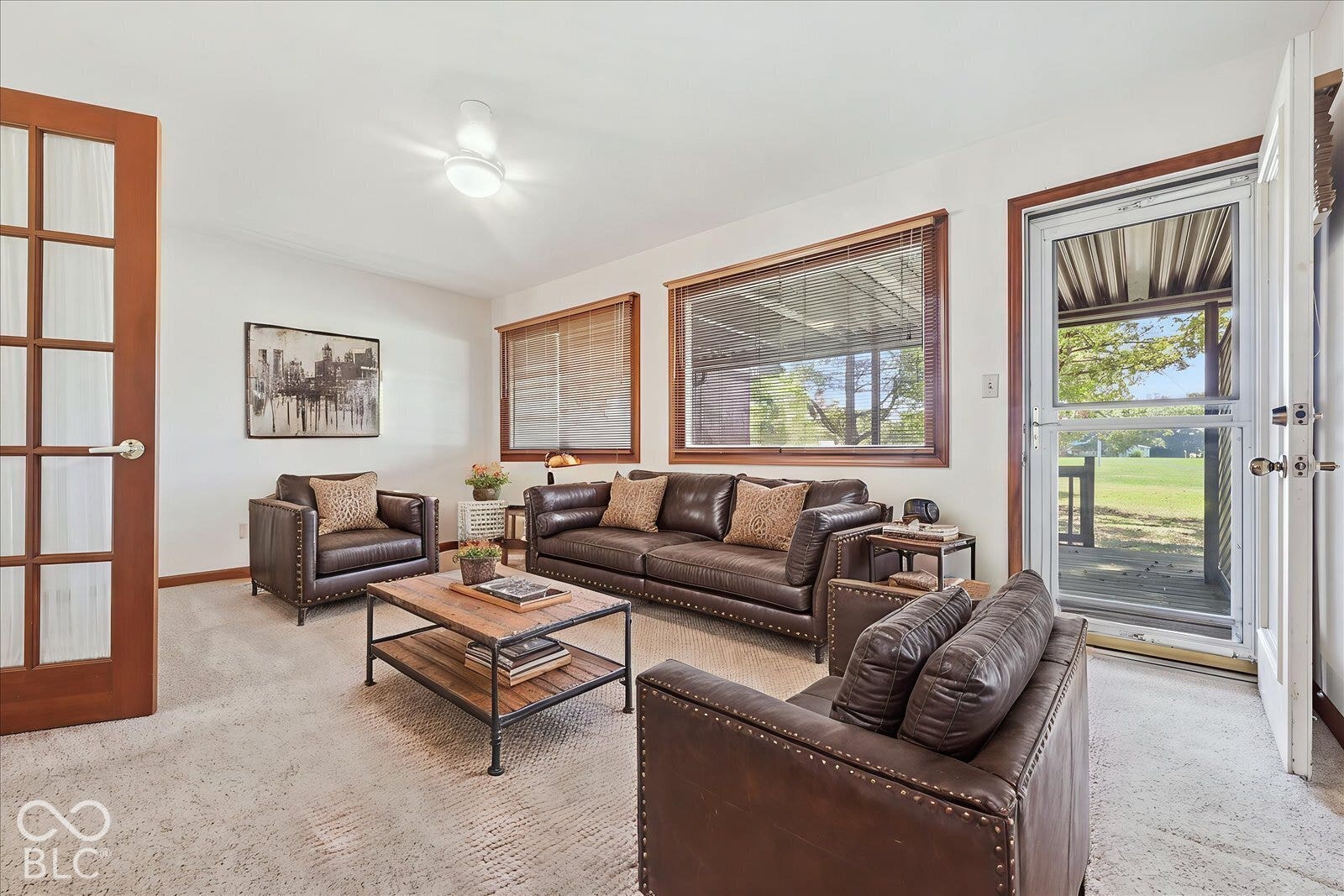 Virtually Altered - Sun Room- virtually staged with different furniture, featuring wood-trimmed windows, a multi-pane glass door, neutral carpeting, and a central ceiling light fixture