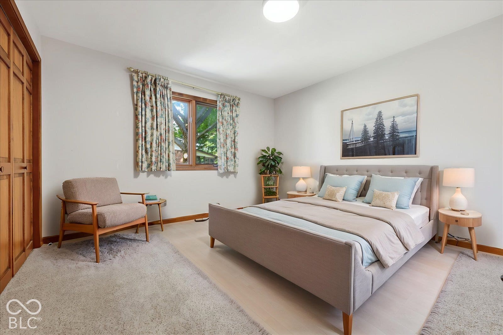 Virtually Altered - Bedroom two -Natural light-filled room featuring wood-trim window casing and wood-finish sliding closet doors