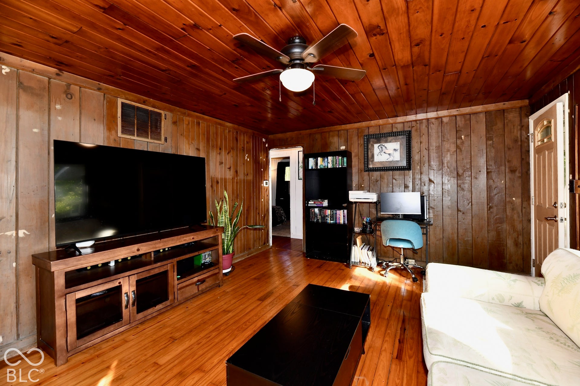 Wood-paneled walls and ceiling with a ceiling fan