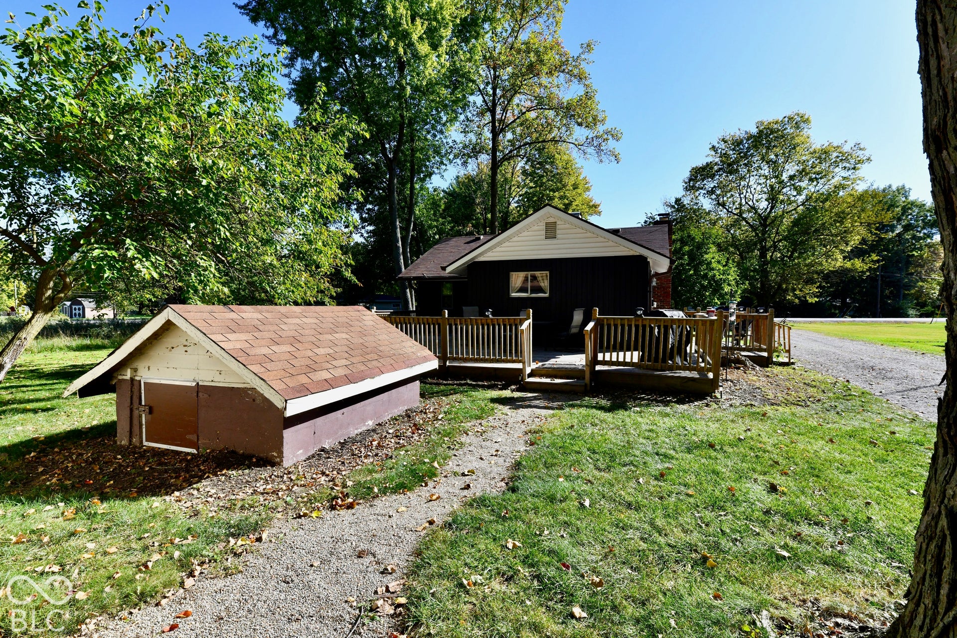 Exterior features a wood deck, gravel path, and a storage shed with a shingled roof