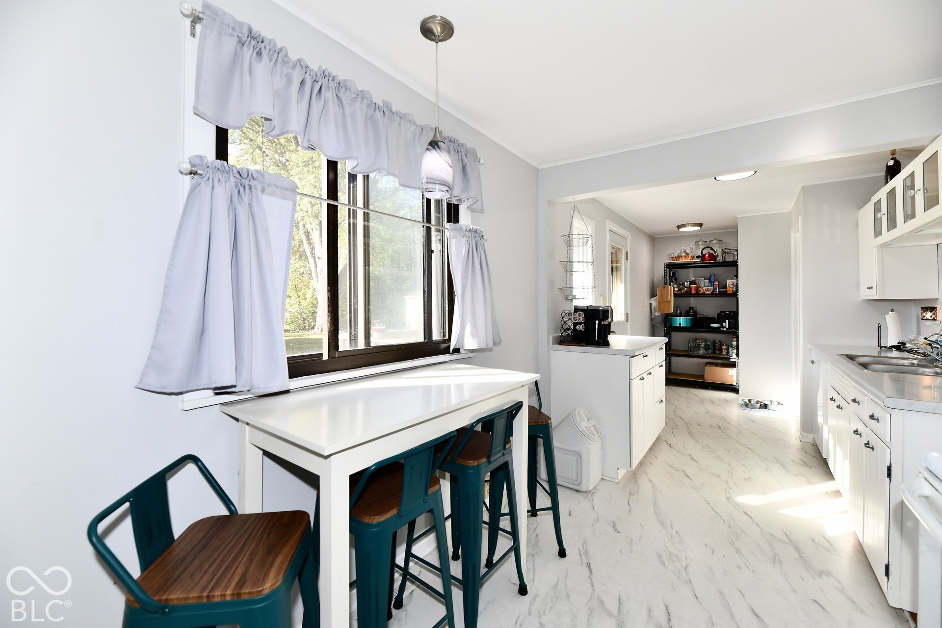 White cabinetry, light-toned flooring, and a single-basin sink with a chrome faucet